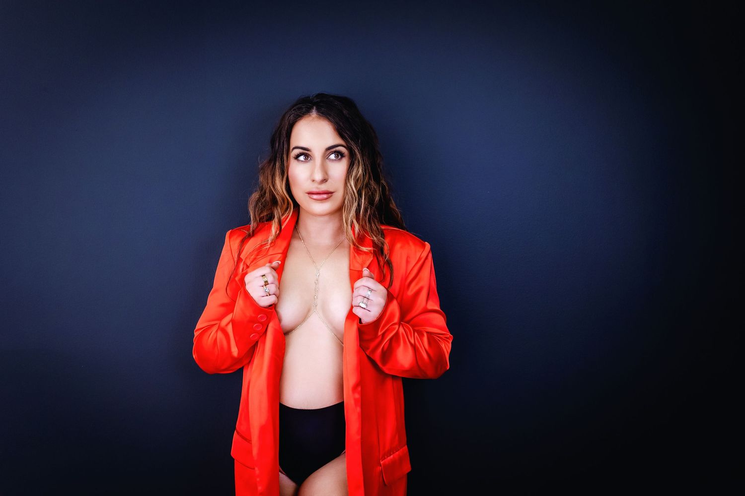 Person wearing bright red jacket against dark background in artistic portrait.