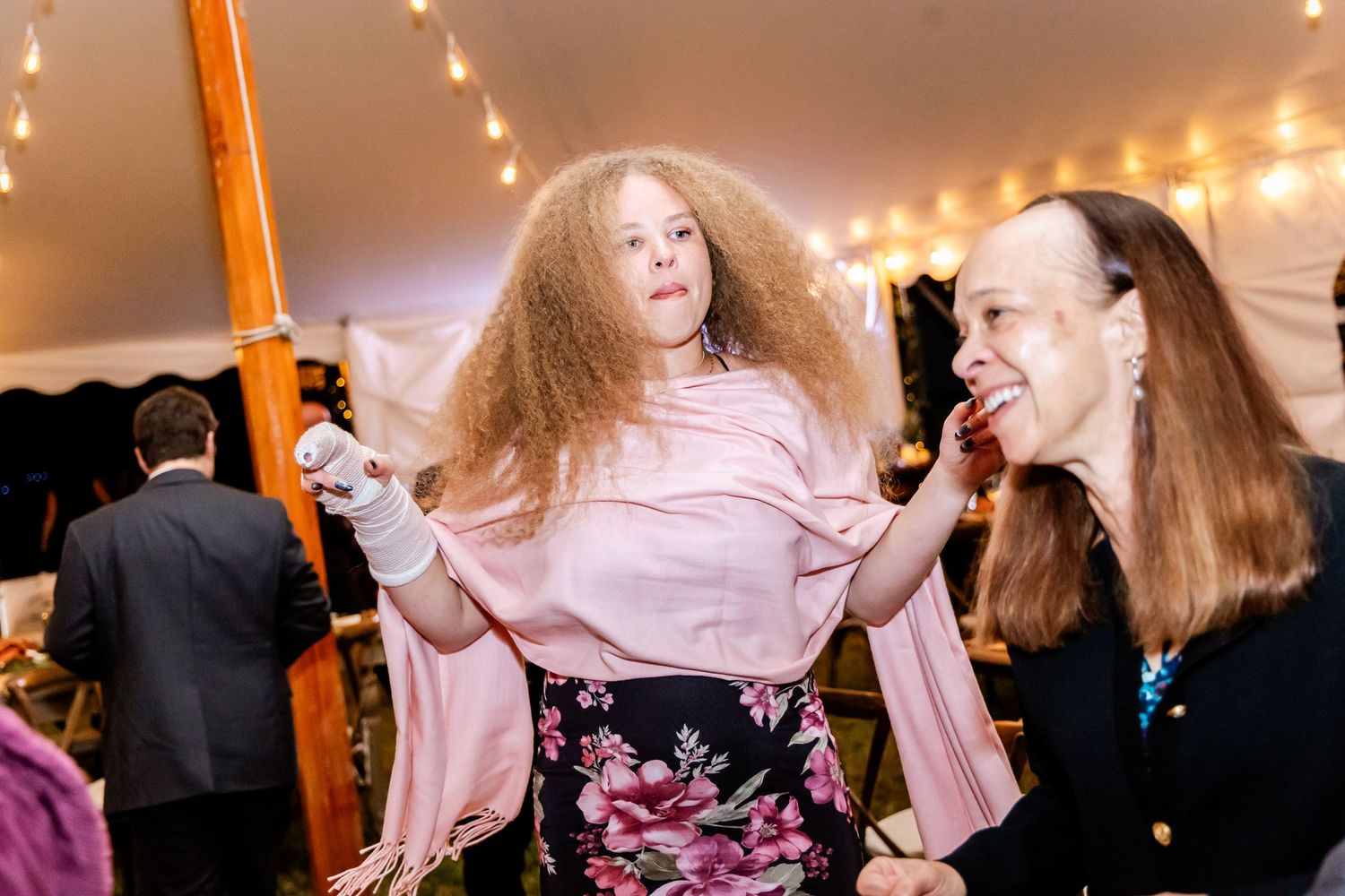 Wedding guests dancing and celebrating on a dimly lit dance floor under string lights.