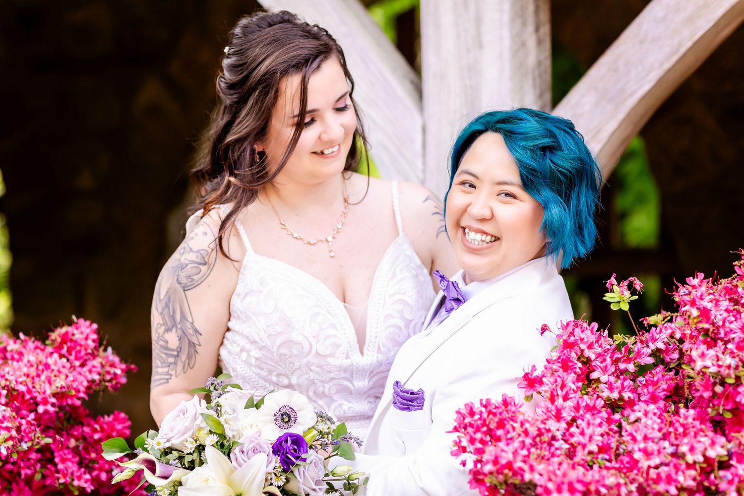 A candid wedding portrait showing joyful expressions amidst pink azalea blooms.