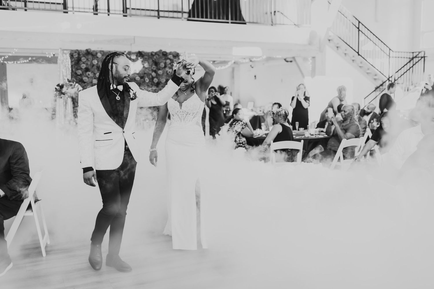 Black and white photo captures dramatic wedding dance moment with guests watching.
