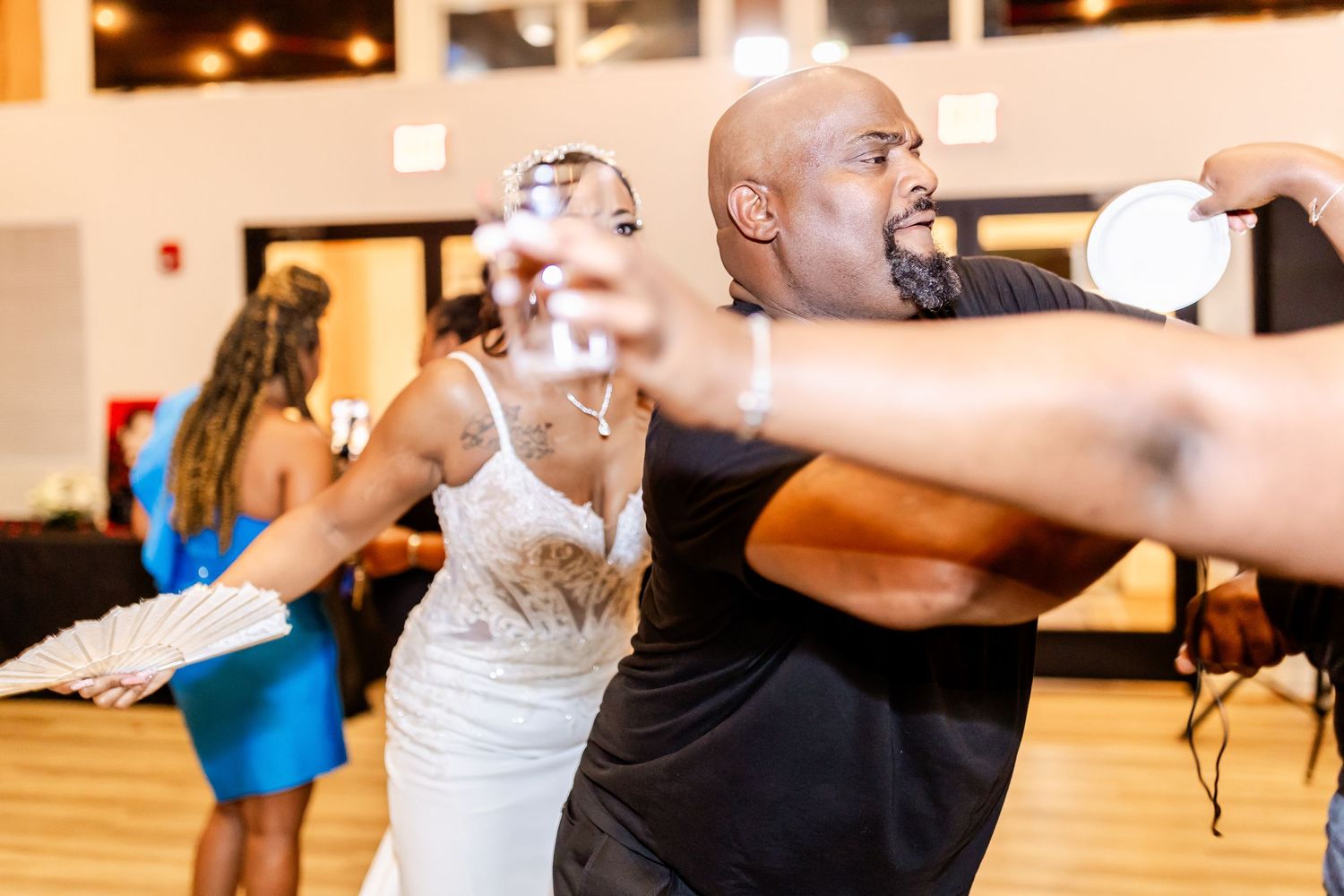 People dancing energetically in an indoor dance studio with a wooden floor.