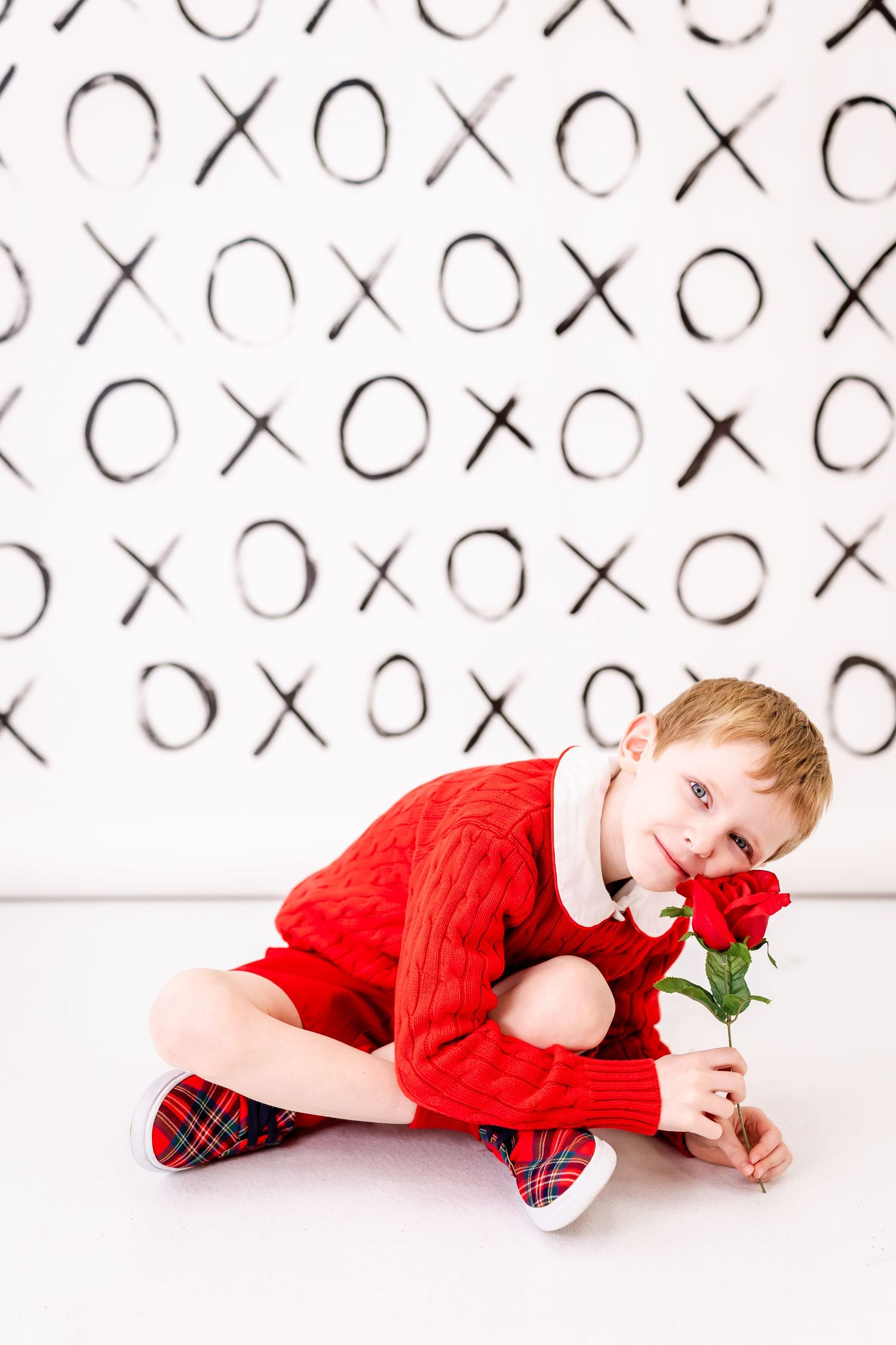 A sweet Valentine's scene with a red sweater and rose against a black and white XO pattern background.