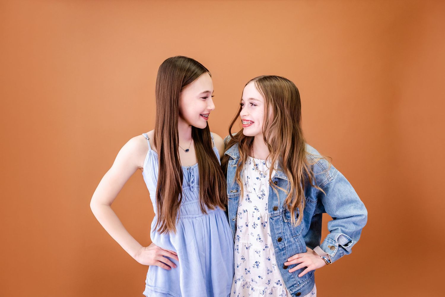 Casual family portrait session against orange background with coordinated blue and white outfits.