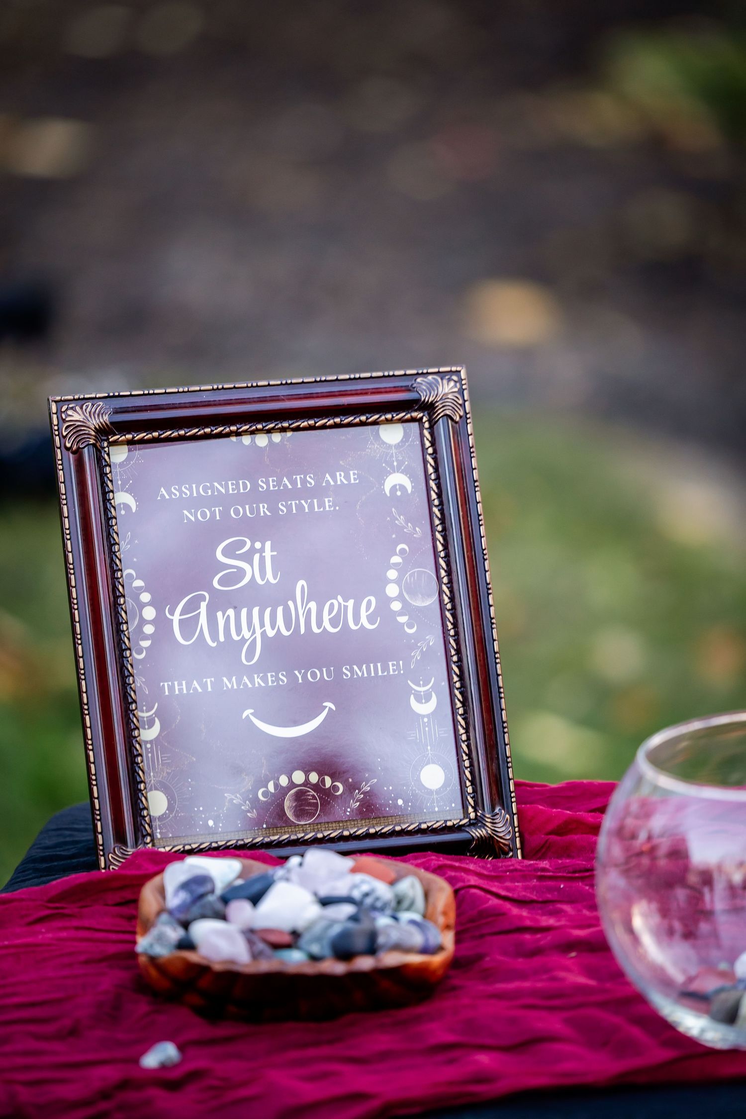 Wedding signage displayed on burgundy velvet with decorative text and frames.