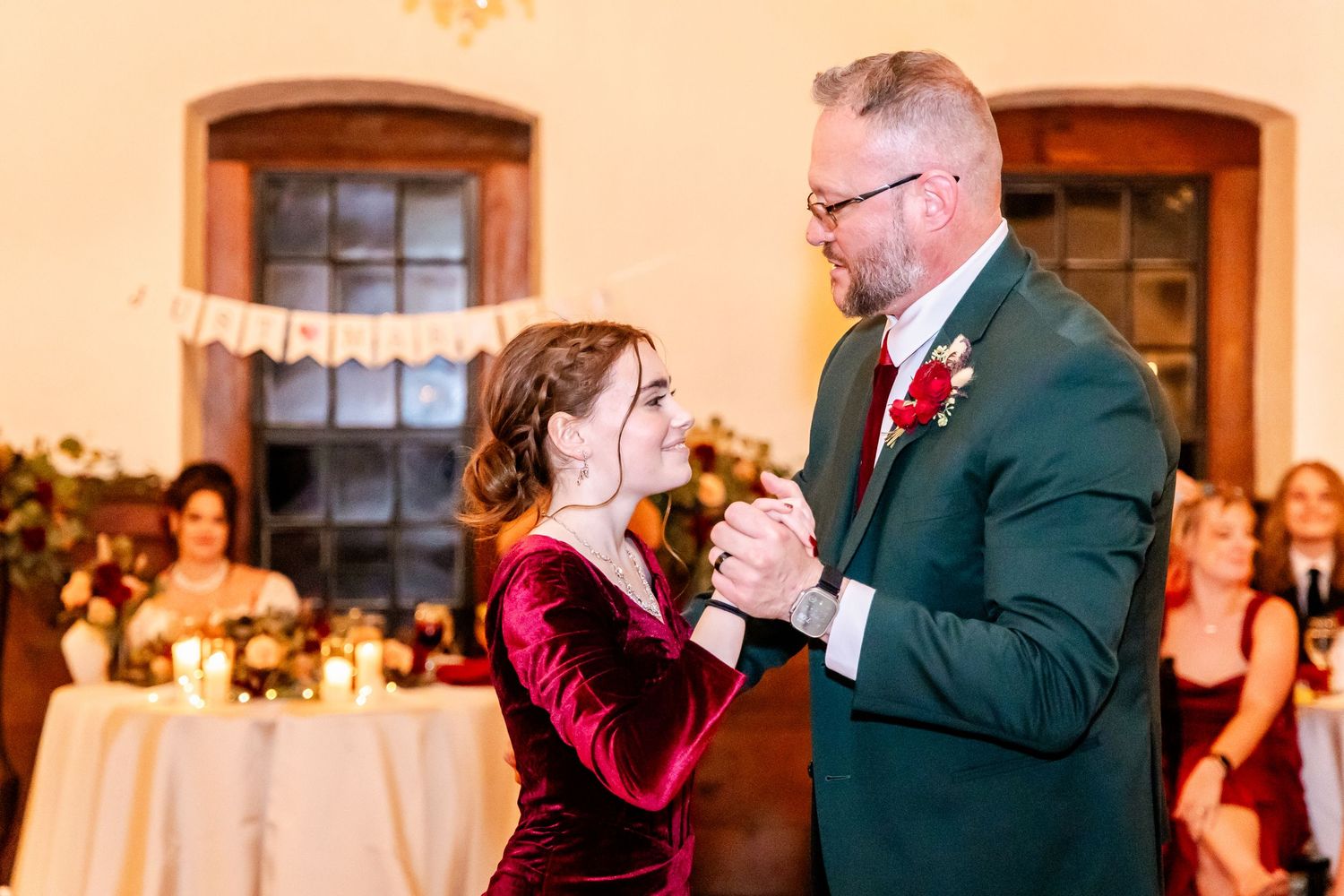 Joyful celebration at an elegant wedding reception with warm lighting and wooden beams overhead.