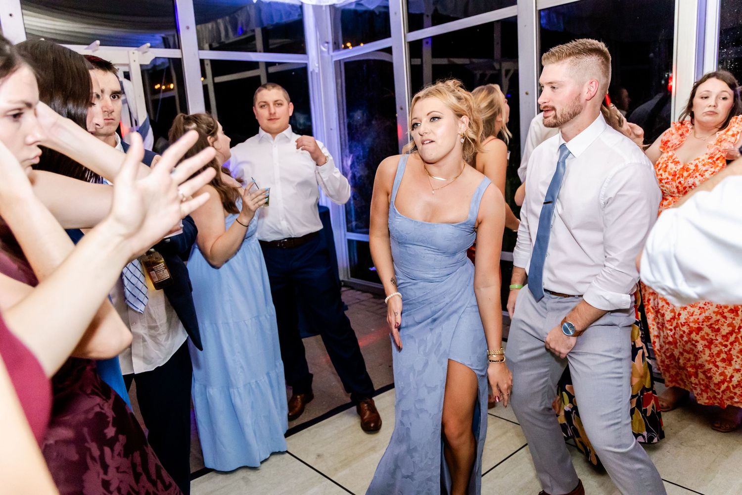 Guests in formal attire dancing at a wedding reception under elegant white draping.