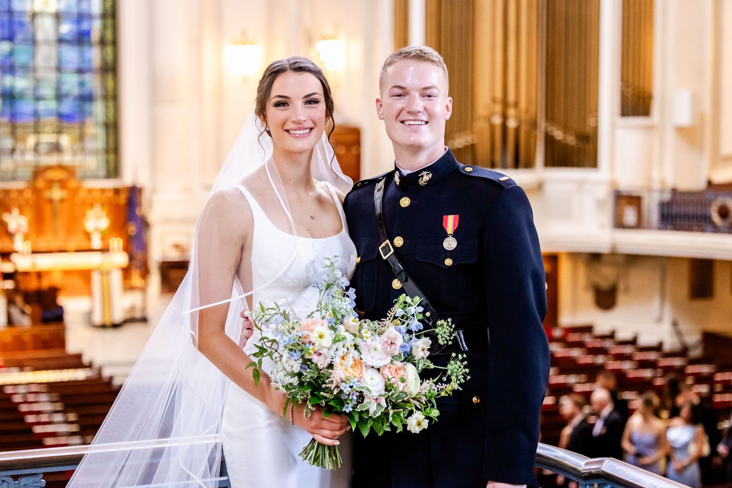 Wedding couple and military service member pose for formal portraits in church sanctuary.