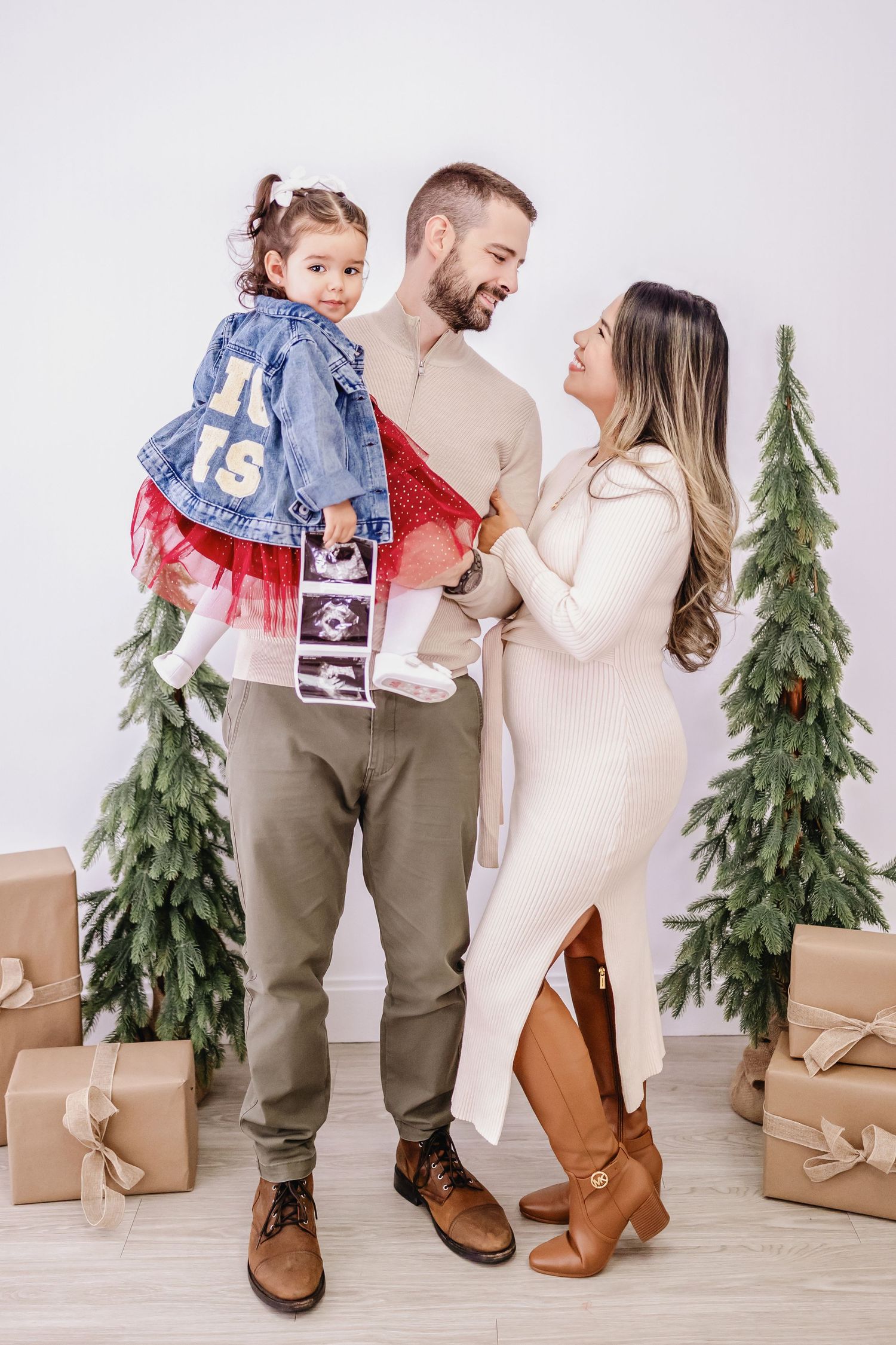 Family holiday portraits with pine trees and brown paper wrapped gifts.