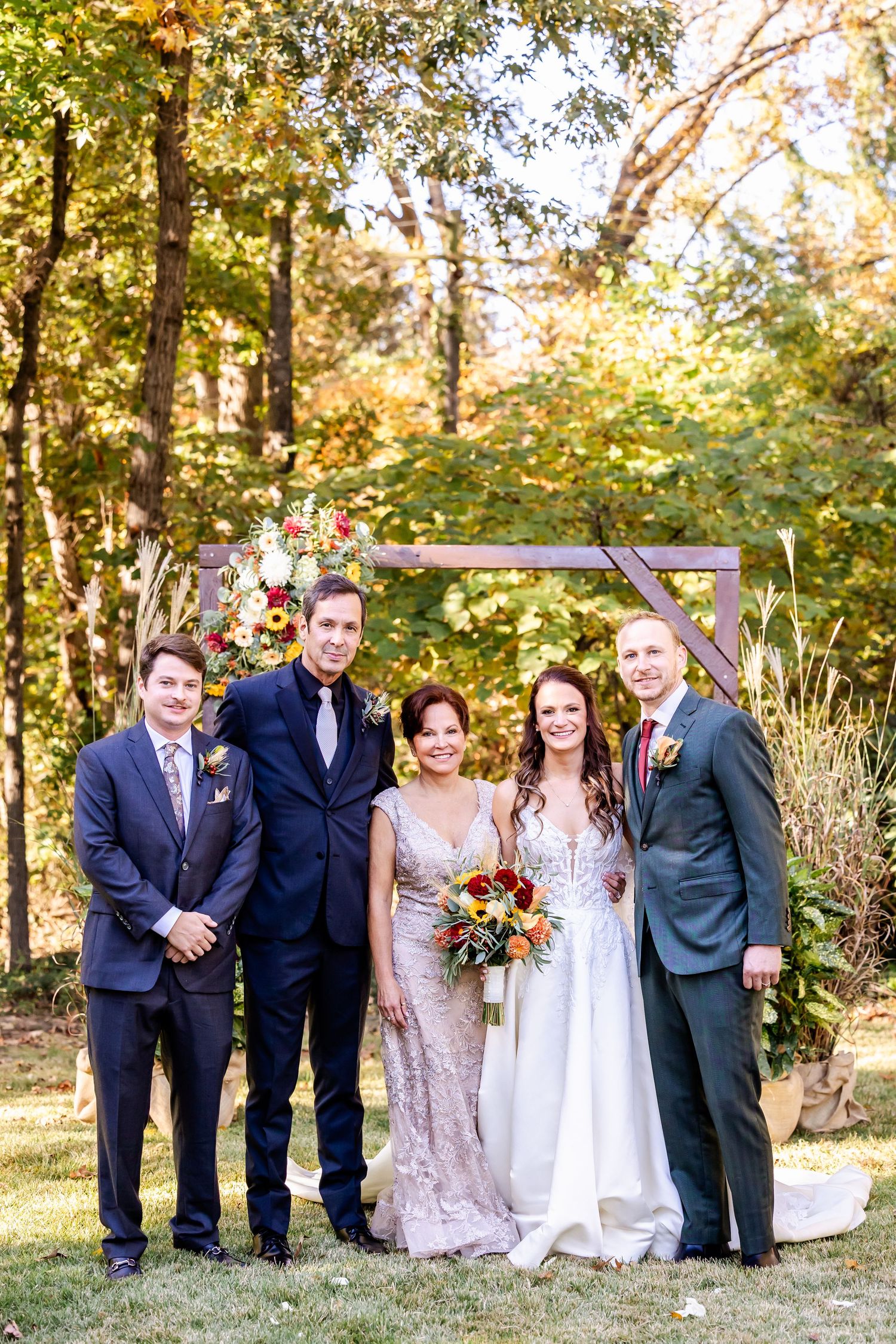Wedding party poses together outdoors in formal attire during fall season.