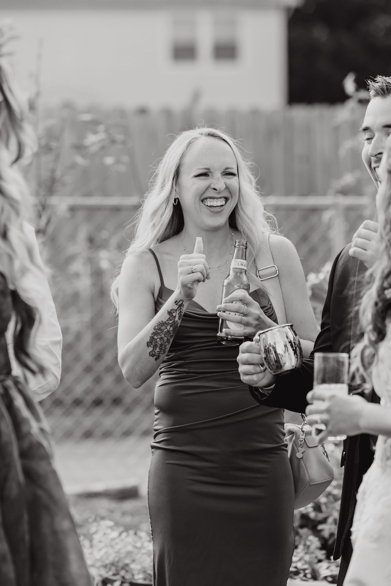 Bridesmaids in black dresses laugh and celebrate together during wedding festivities.