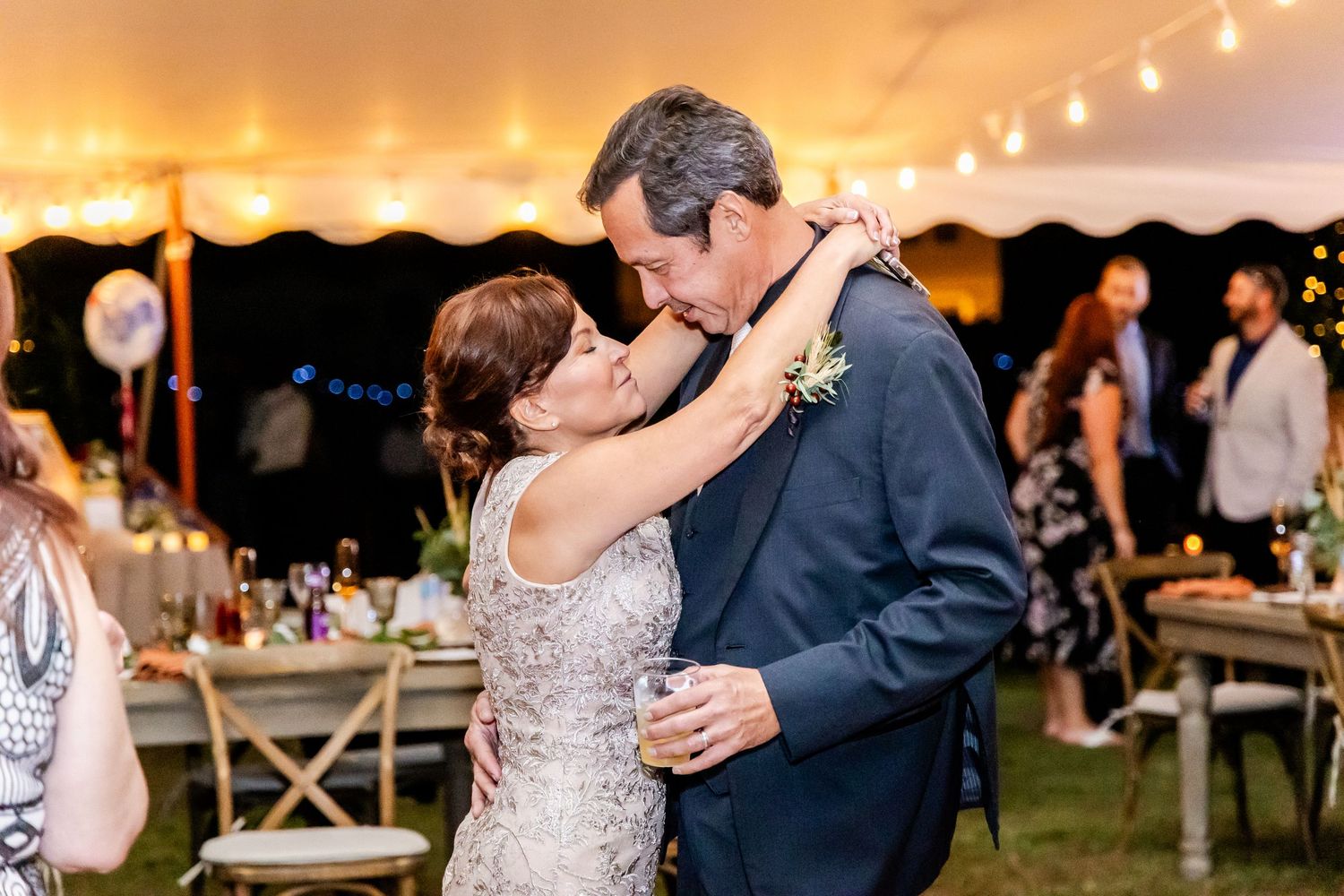 Couples dance together during a romantic evening wedding reception under string lights.