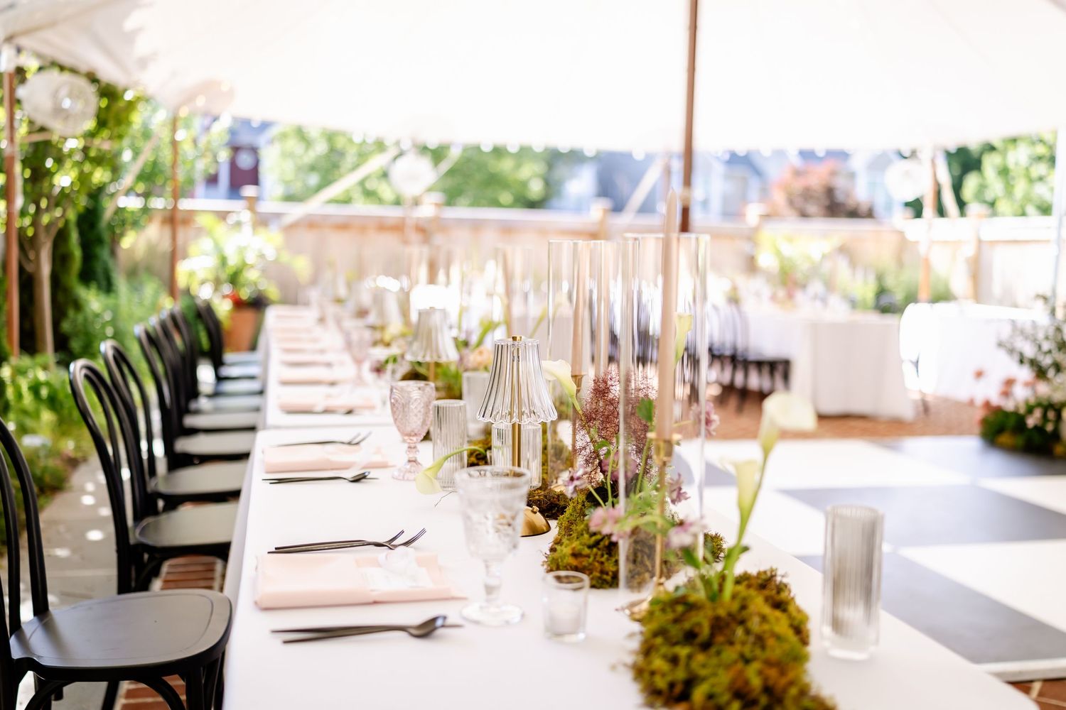 Elegant wedding reception tables set with white linens, floral centerpieces and lanterns.