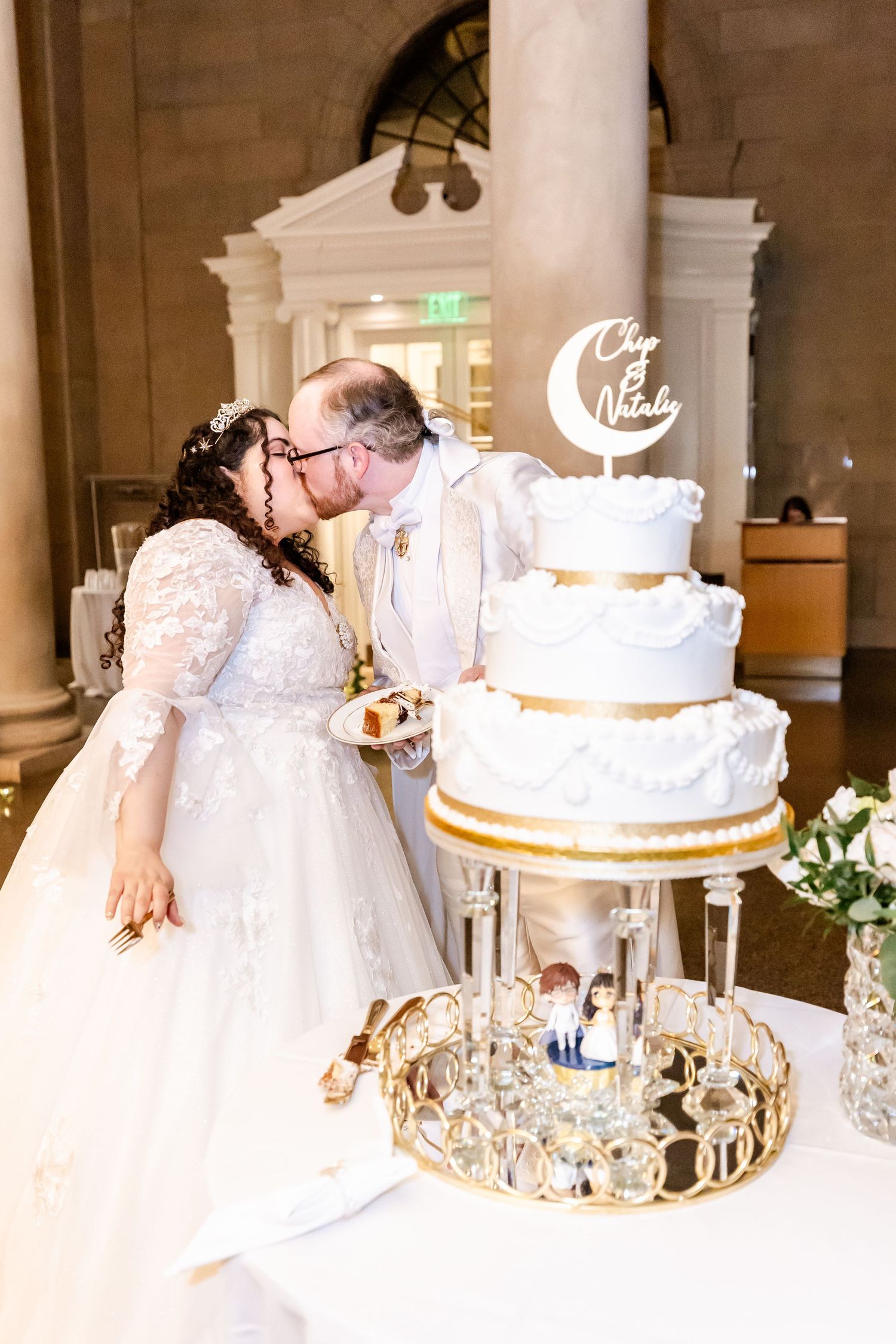 Newlyweds sharing their first kiss during cake cutting ceremony.