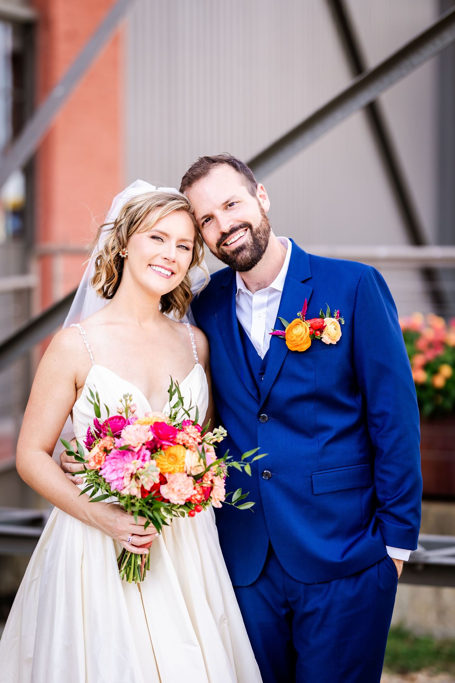 Joyful wedding portrait featuring bright floral bouquet and navy blue suit.
