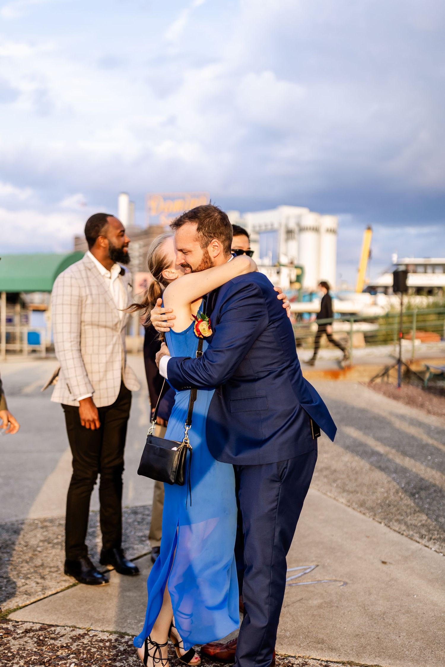 Couple embraces on outdoor pathway during wedding celebrations.