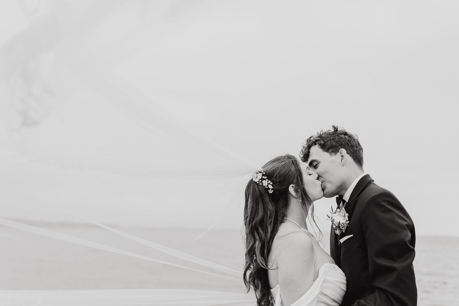 A couple embraces on a misty beach shoreline during their wedding photography session.