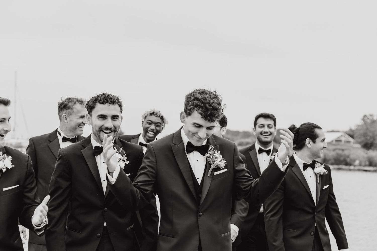 Black and white photo of groomsmen laughing together outdoors.