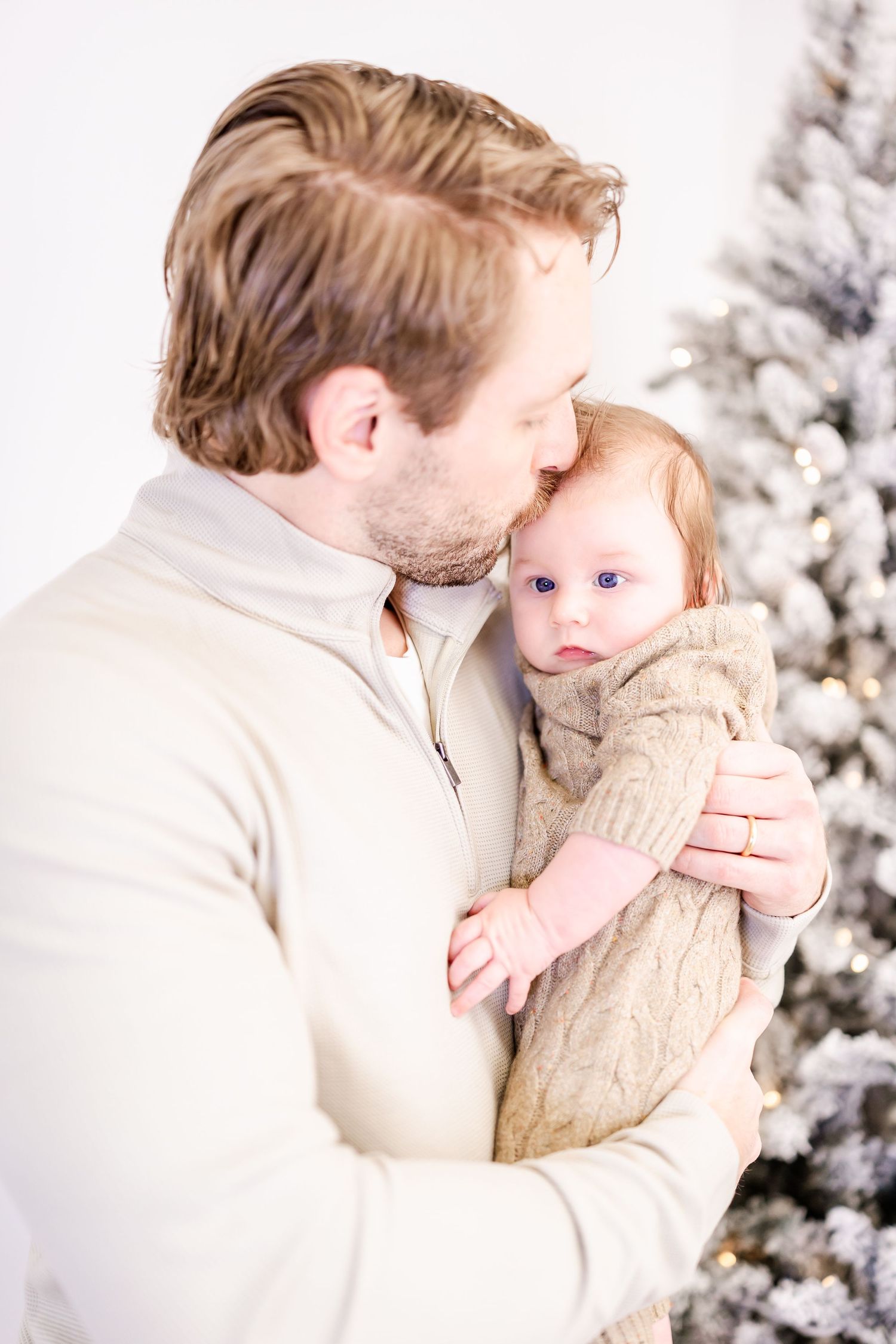 A tender winter family moment with snowy Christmas trees in the background.