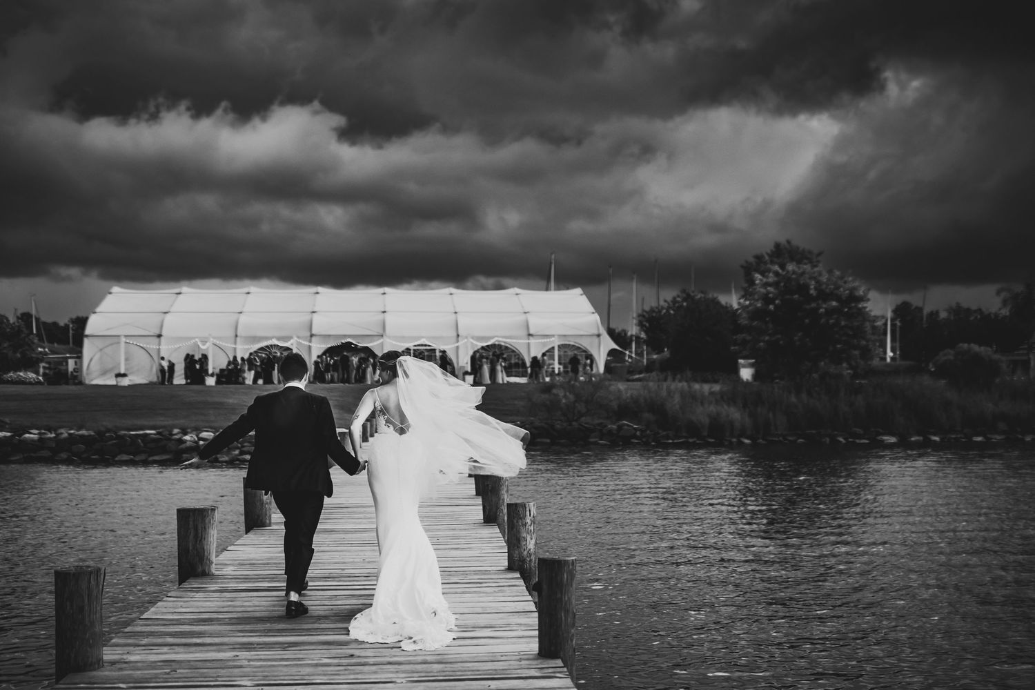 A dramatic black and white wedding series showing joyful moments and scenic water views at a lakeside celebration.
