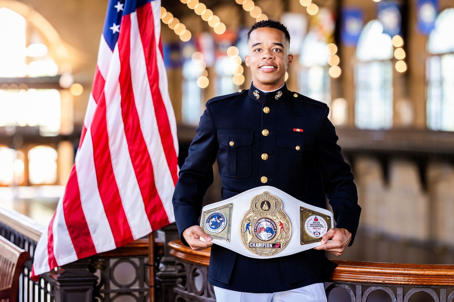 Military service member in dress uniform posing with American flags and medals.