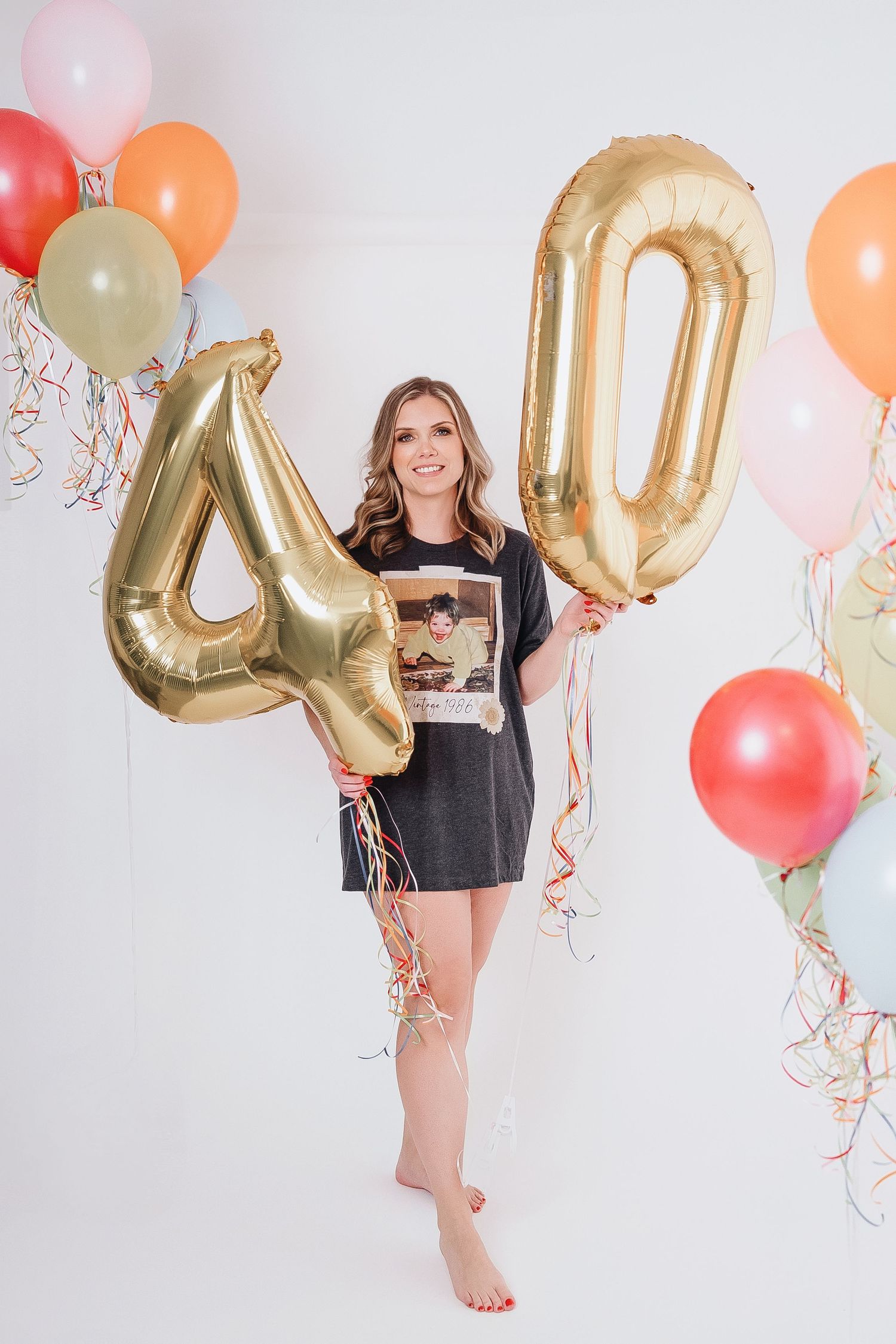 Birthday celebration photoshoot with colorful balloons and gold number decorations.