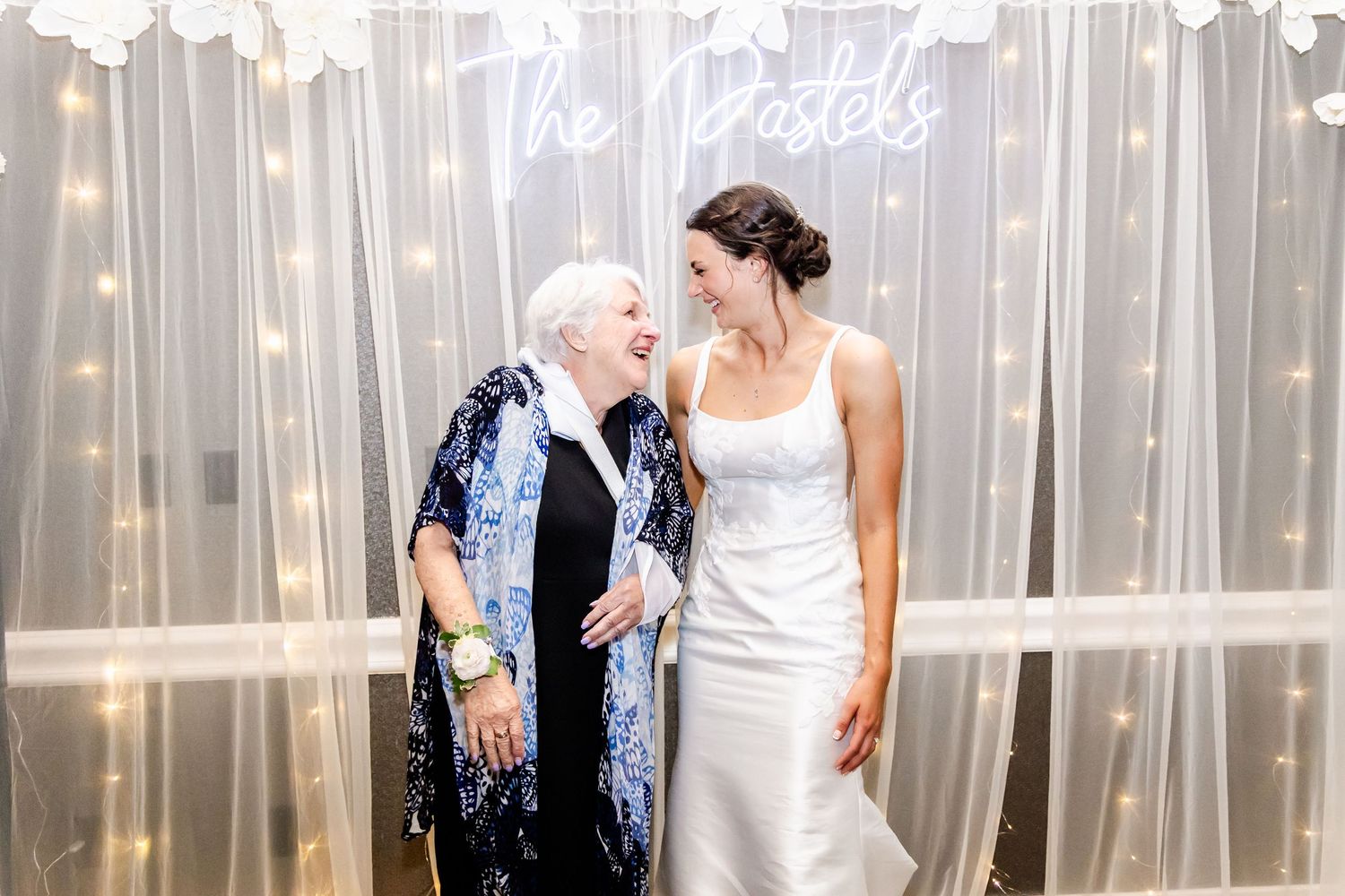 Wedding party members sharing a candid moment in front of a sheer curtain backdrop.
