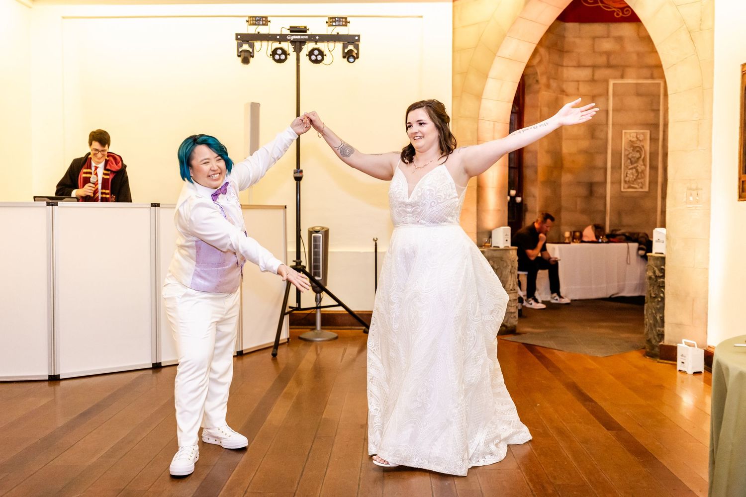 Couple performs energetic dance moves in elegant venue with wooden floors and arched doorways.