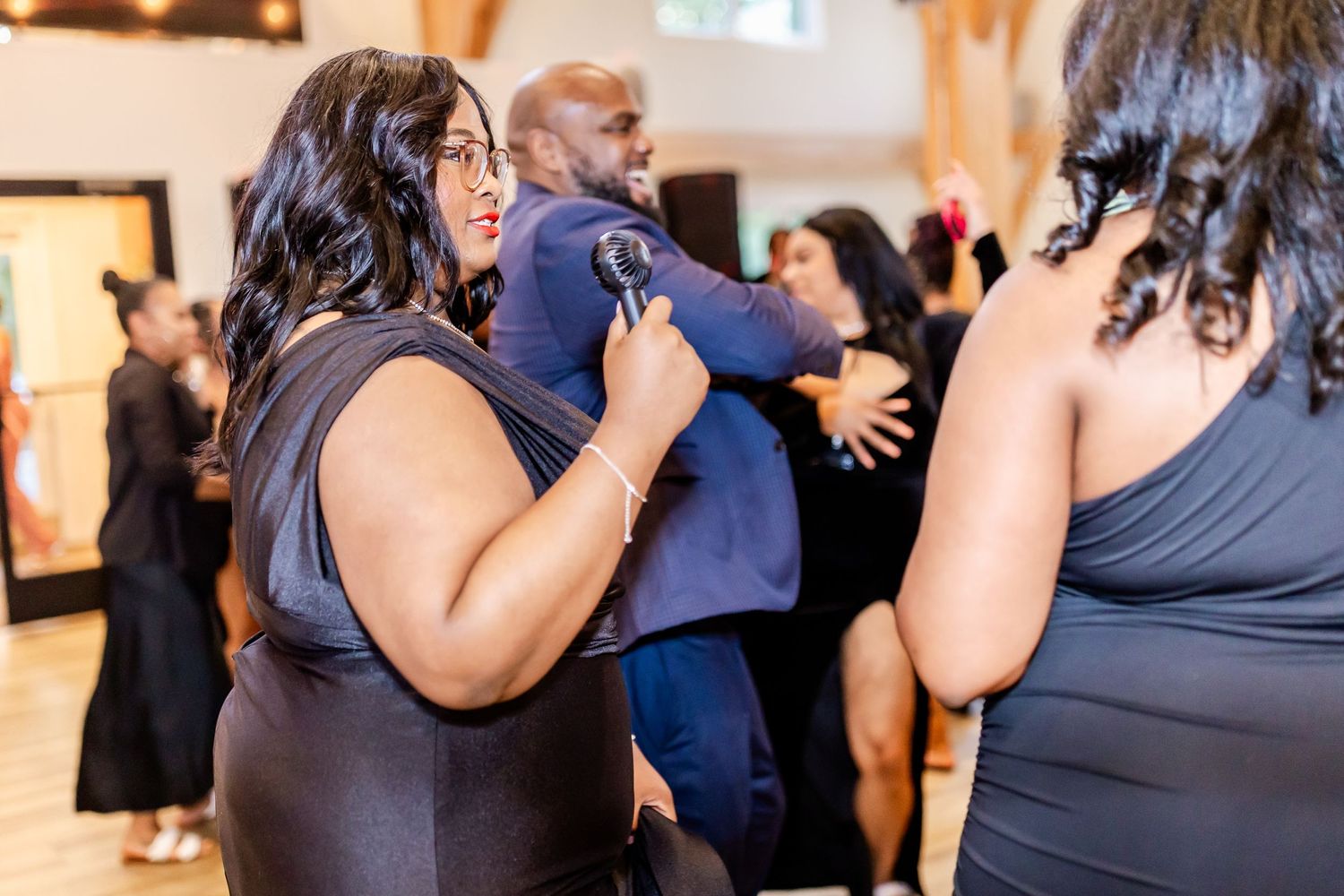 People dancing and socializing at an indoor event with wooden flooring.