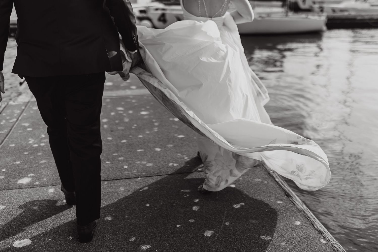 Black and white photo of flowing wedding dress fabric near water.