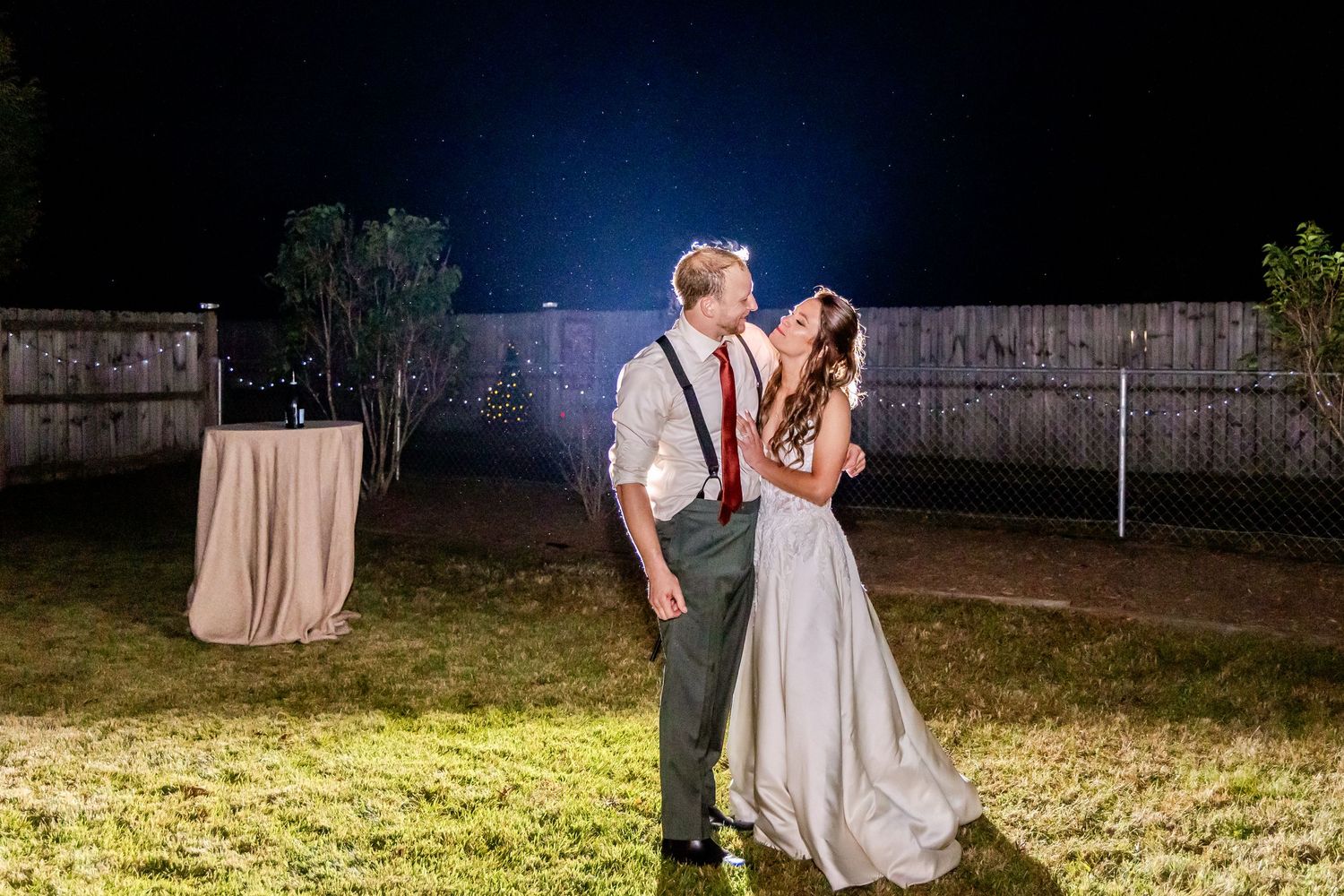 A nighttime wedding dance celebration under outdoor lighting.