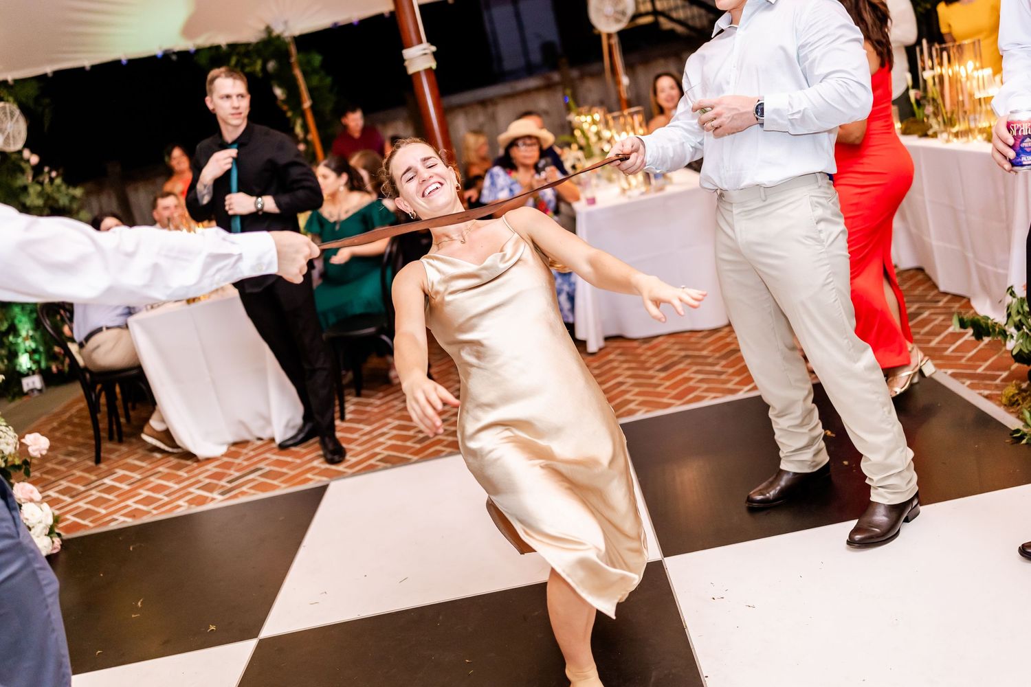 Wedding guests dancing energetically on a checkered dance floor at a reception celebration.