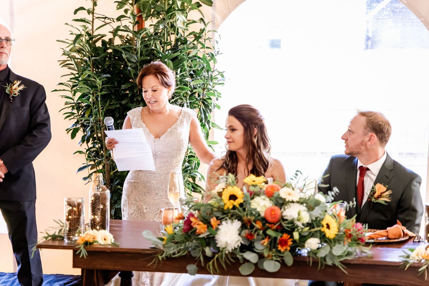 Wedding ceremony setup with white chairs and floral arrangements in an indoor venue.