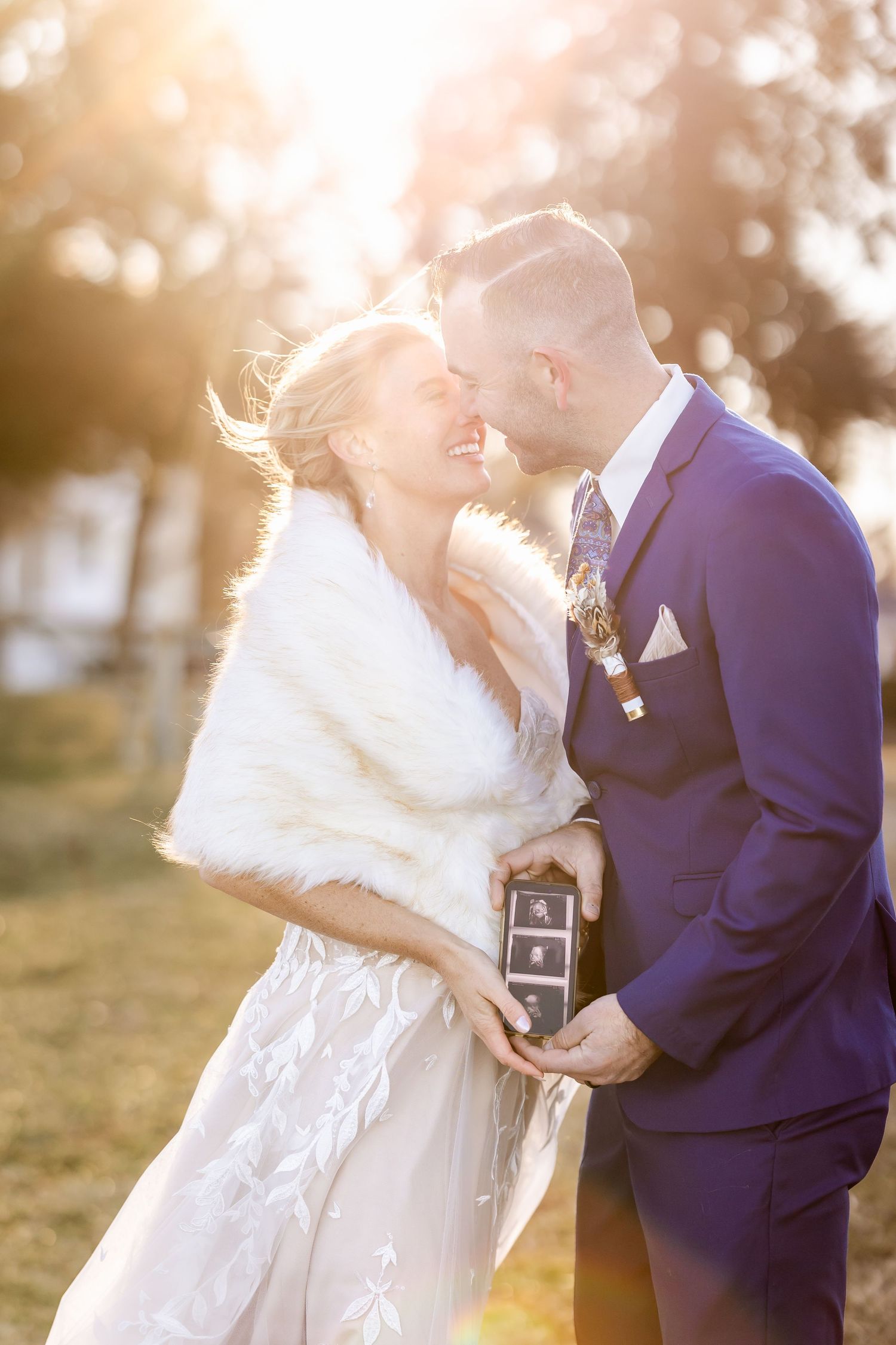 A romantic sunset wedding photo with warm golden light and white fur wrap.