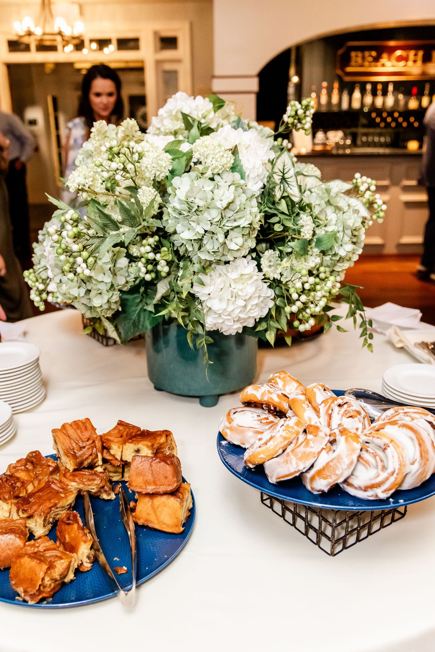 Elegant dessert display featuring pastries and white hydrangea centerpieces on a white tablecloth.