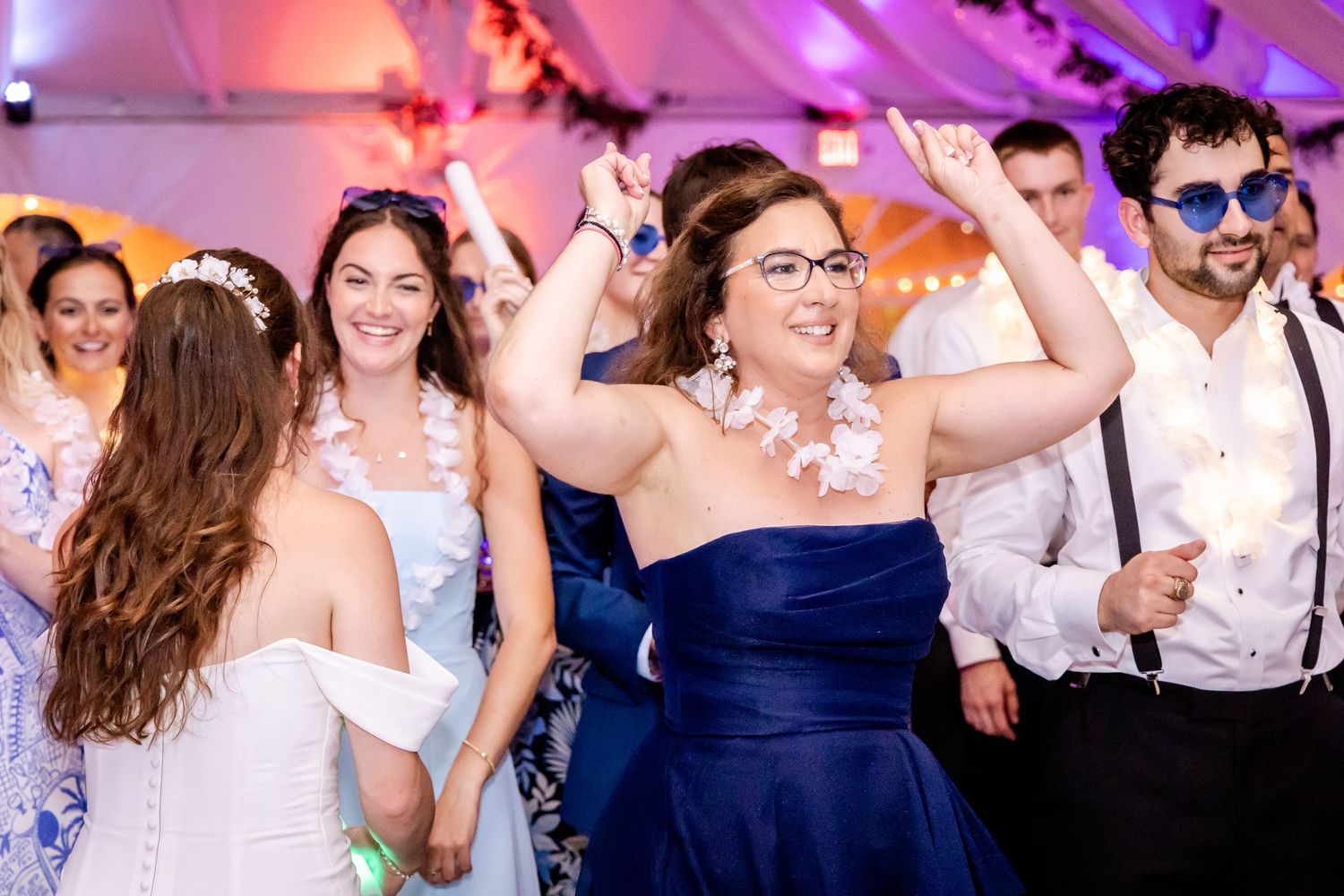 Wedding reception dance floor illuminated with purple lighting as guests celebrate.