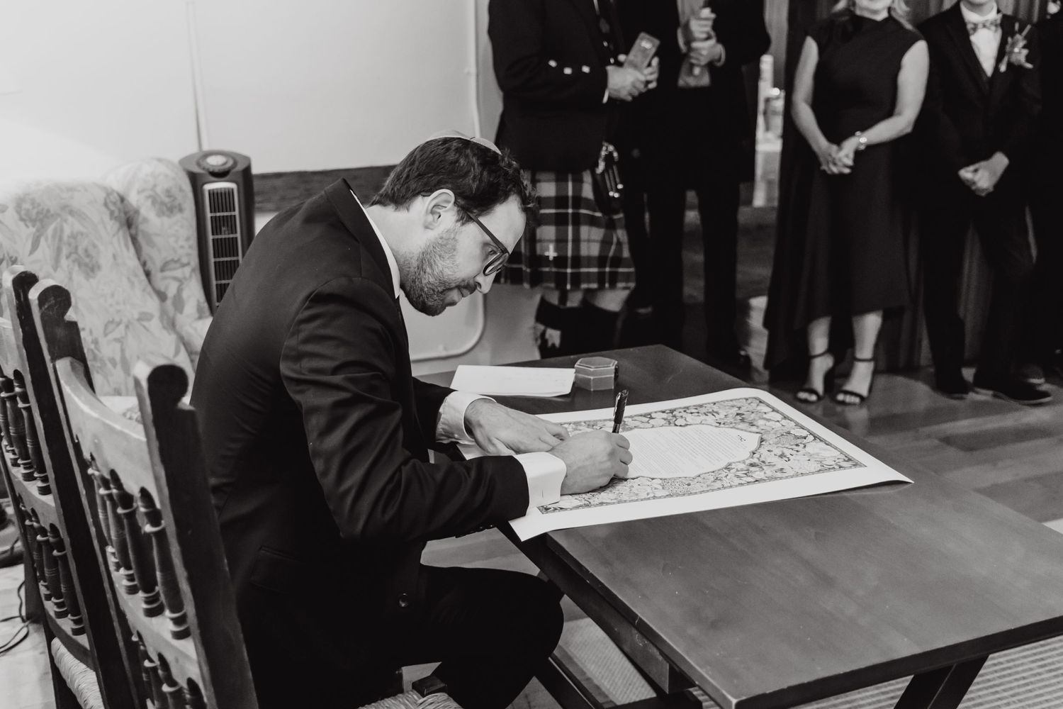 Wedding guest signing guest book at reception in black and white.