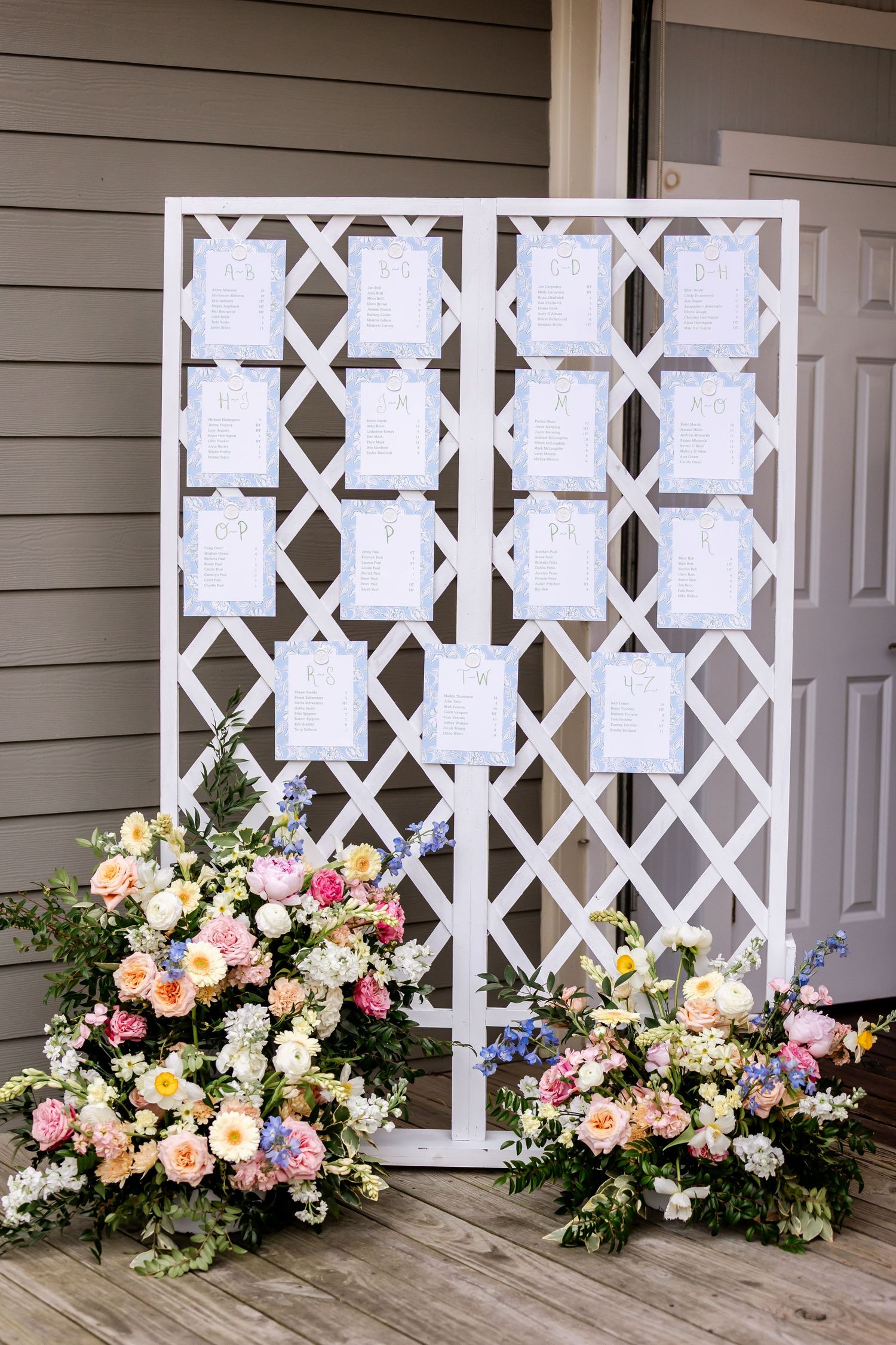 White lattice seating chart display decorated with lush pink and peach floral arrangements.
