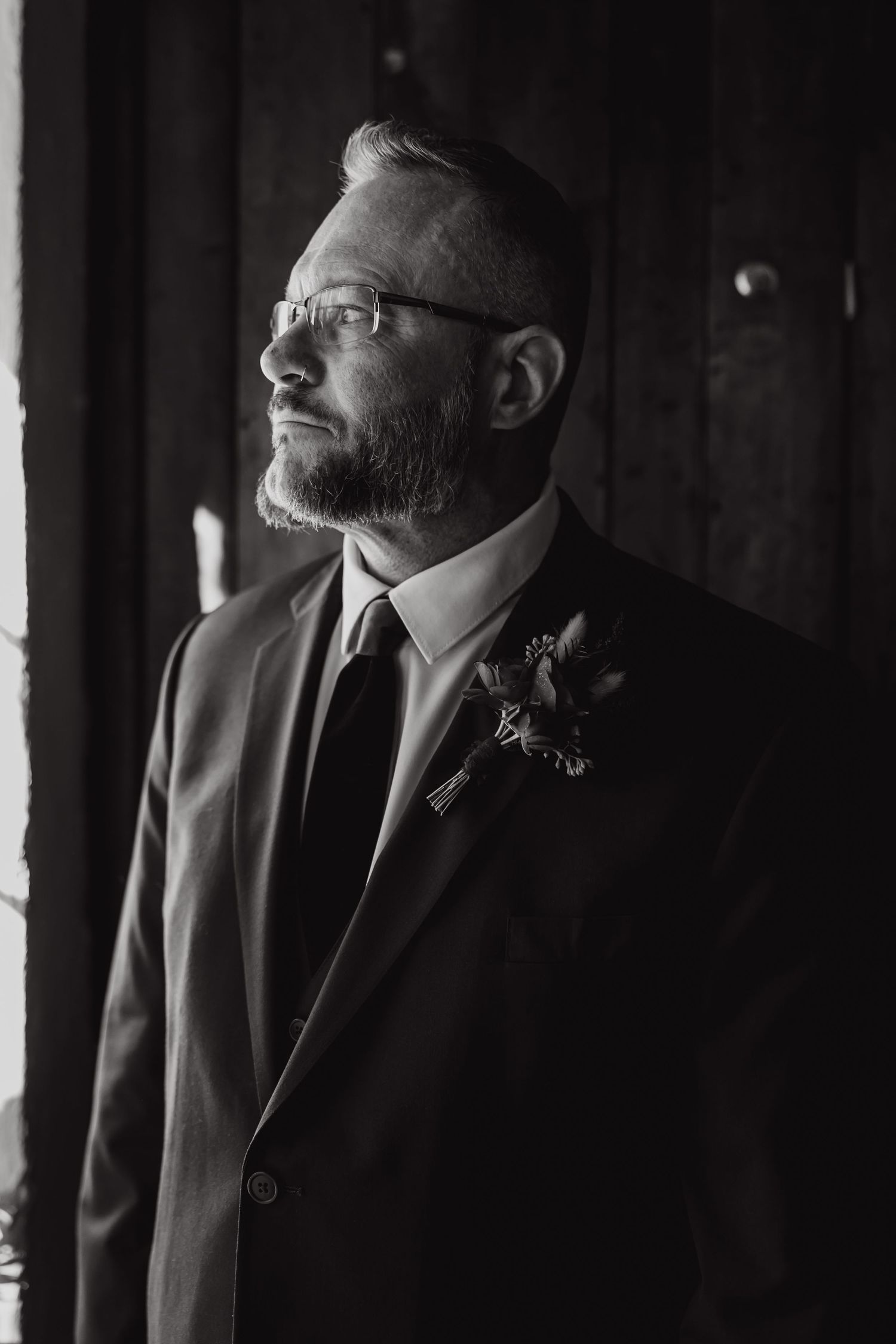 Dramatic black and white portrait showing silhouettes of men in suits against window light.