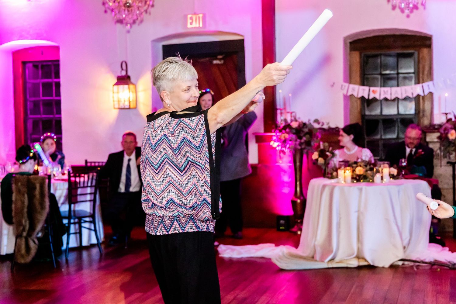 Wedding reception venue decorated with pink uplighting and white accents.