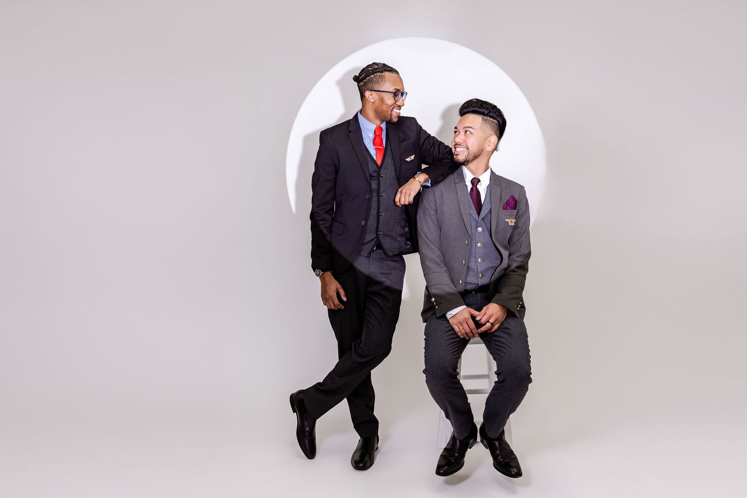 Two people in business attire sit in chairs with their legs crossed, shown in a sequence of poses against a white backdrop.