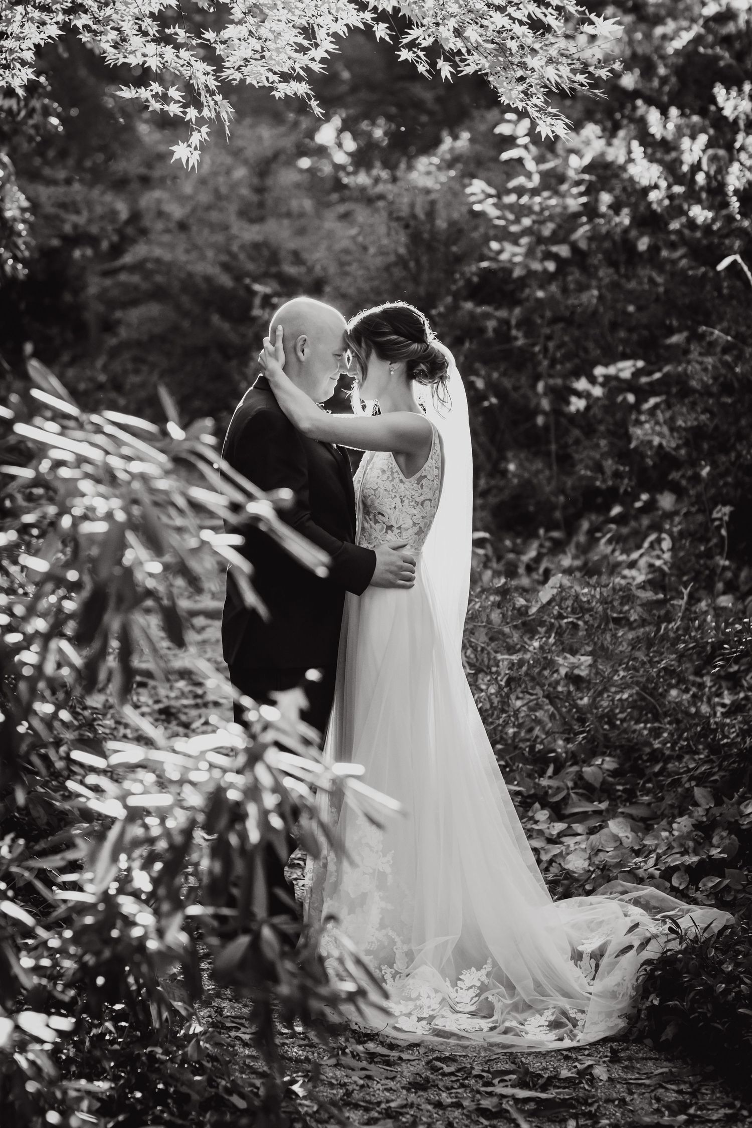 A romantic black and white wedding photoshoot sequence showing a couple embracing in a lush garden setting.
