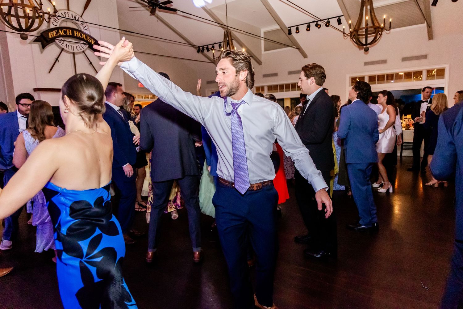 Wedding guests dancing and celebrating on a lively dance floor at an indoor reception venue.