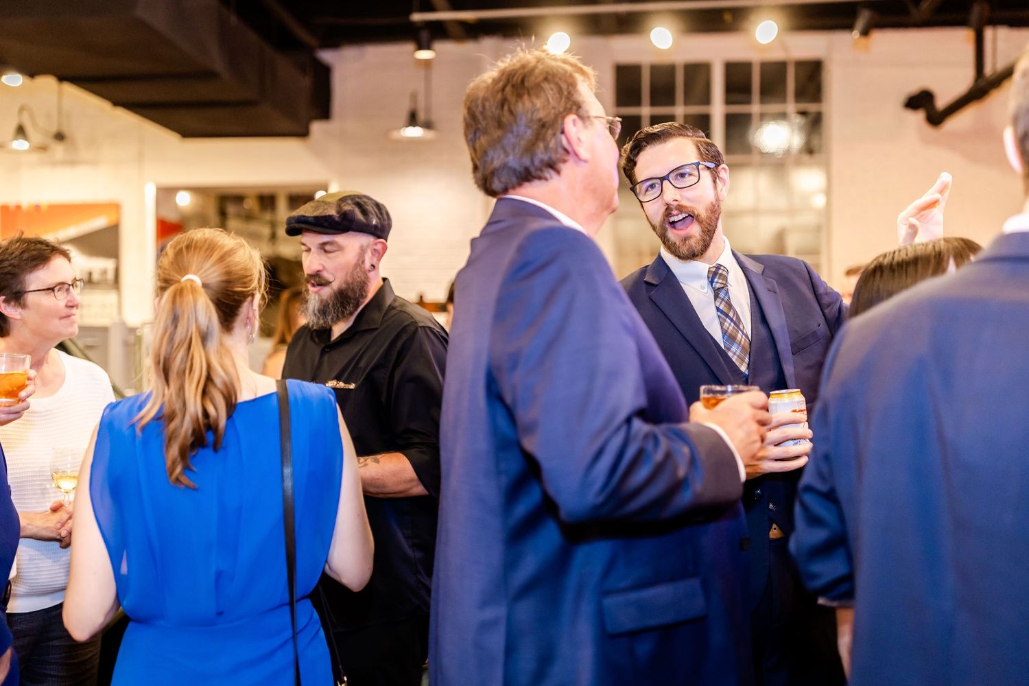 Guests engaged in lively conversation at an indoor social gathering or networking event.