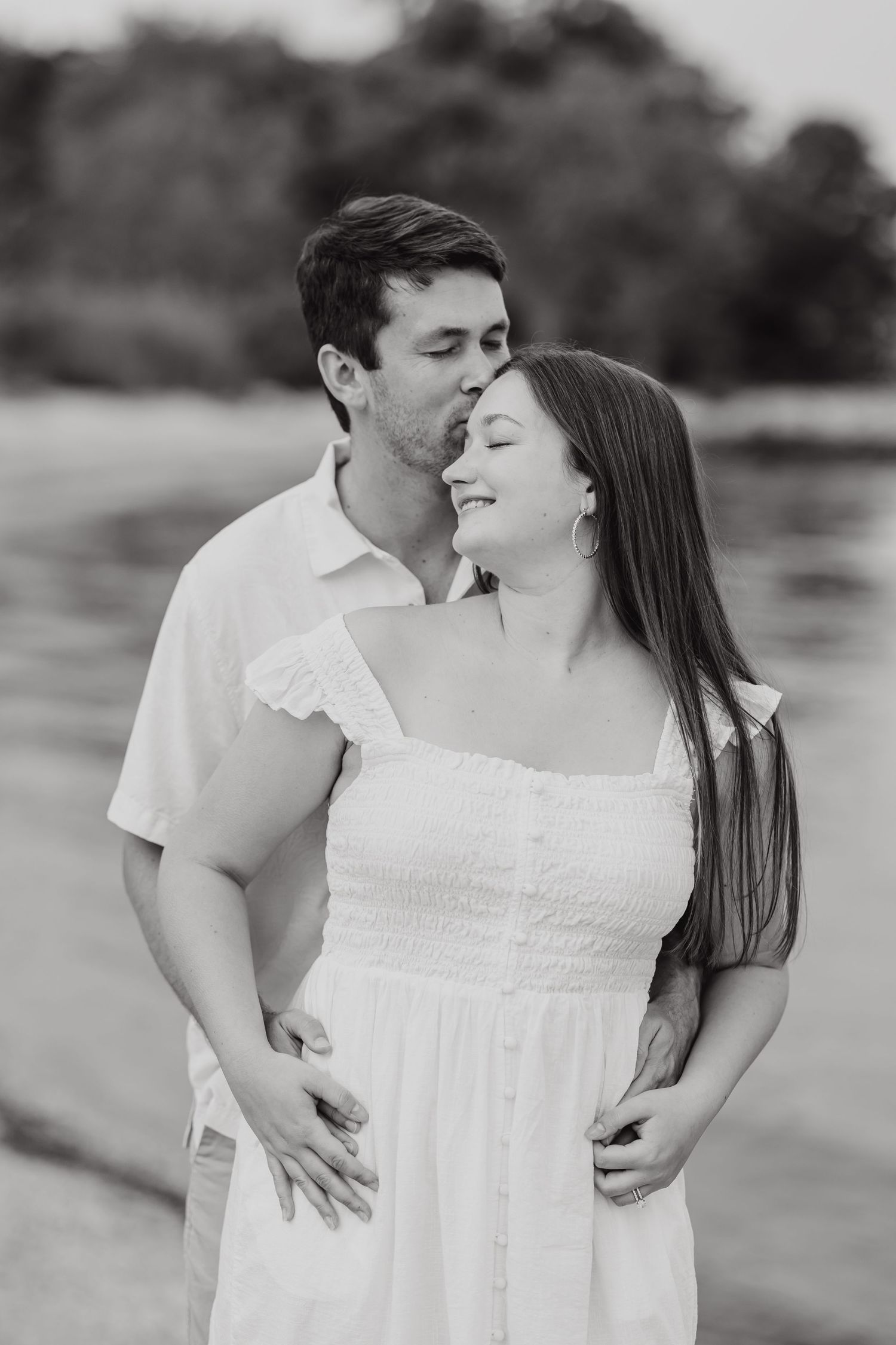 A romantic black and white portrait of a couple embracing on a beach, sharing an intimate moment together.