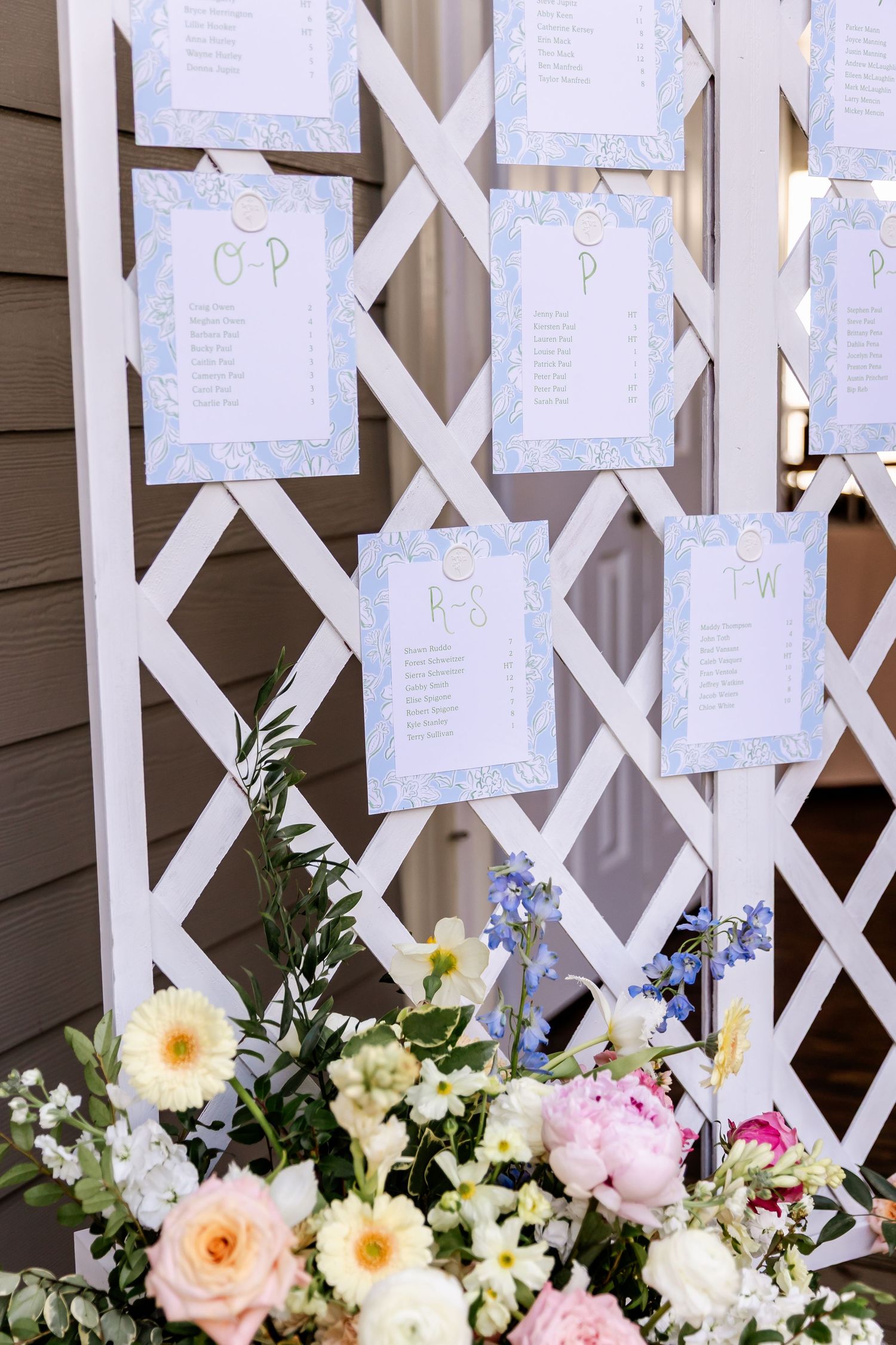 White lattice wedding seating chart display decorated with fresh flowers in pink, yellow and white.