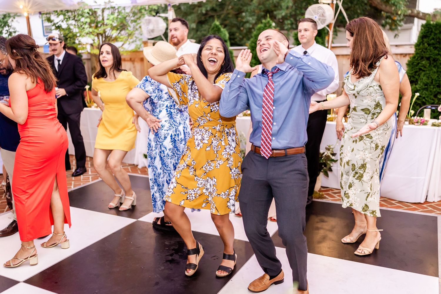 Wedding guests dancing and celebrating on a dance floor at an outdoor reception.