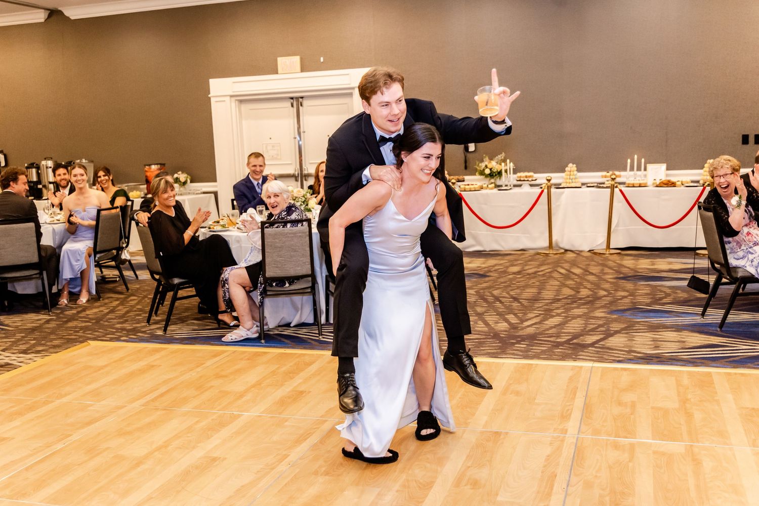 Couple performing their first dance at wedding reception with guests watching in background.