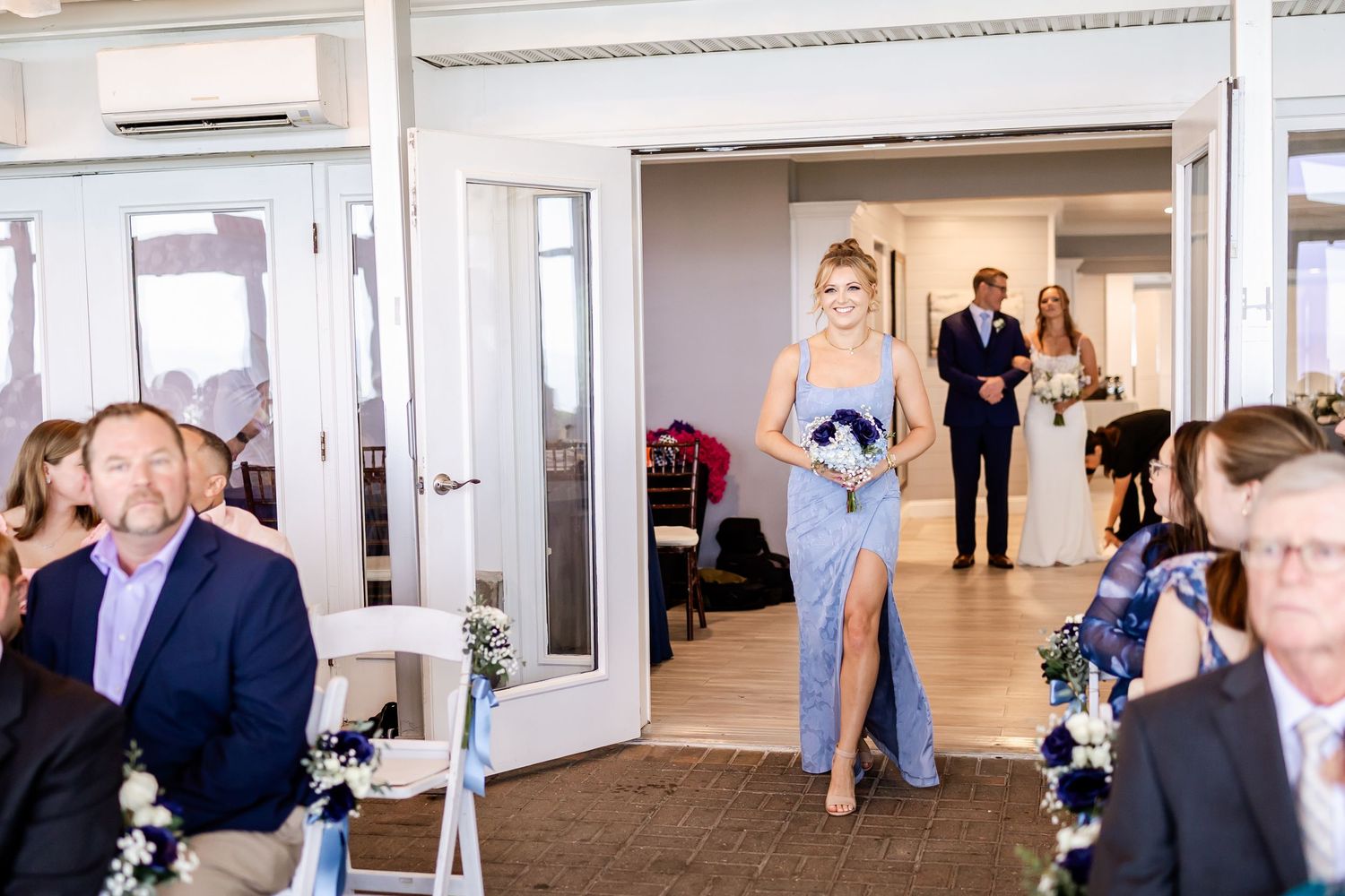 Wedding reception venue setup with guests mingling in bright indoor space.