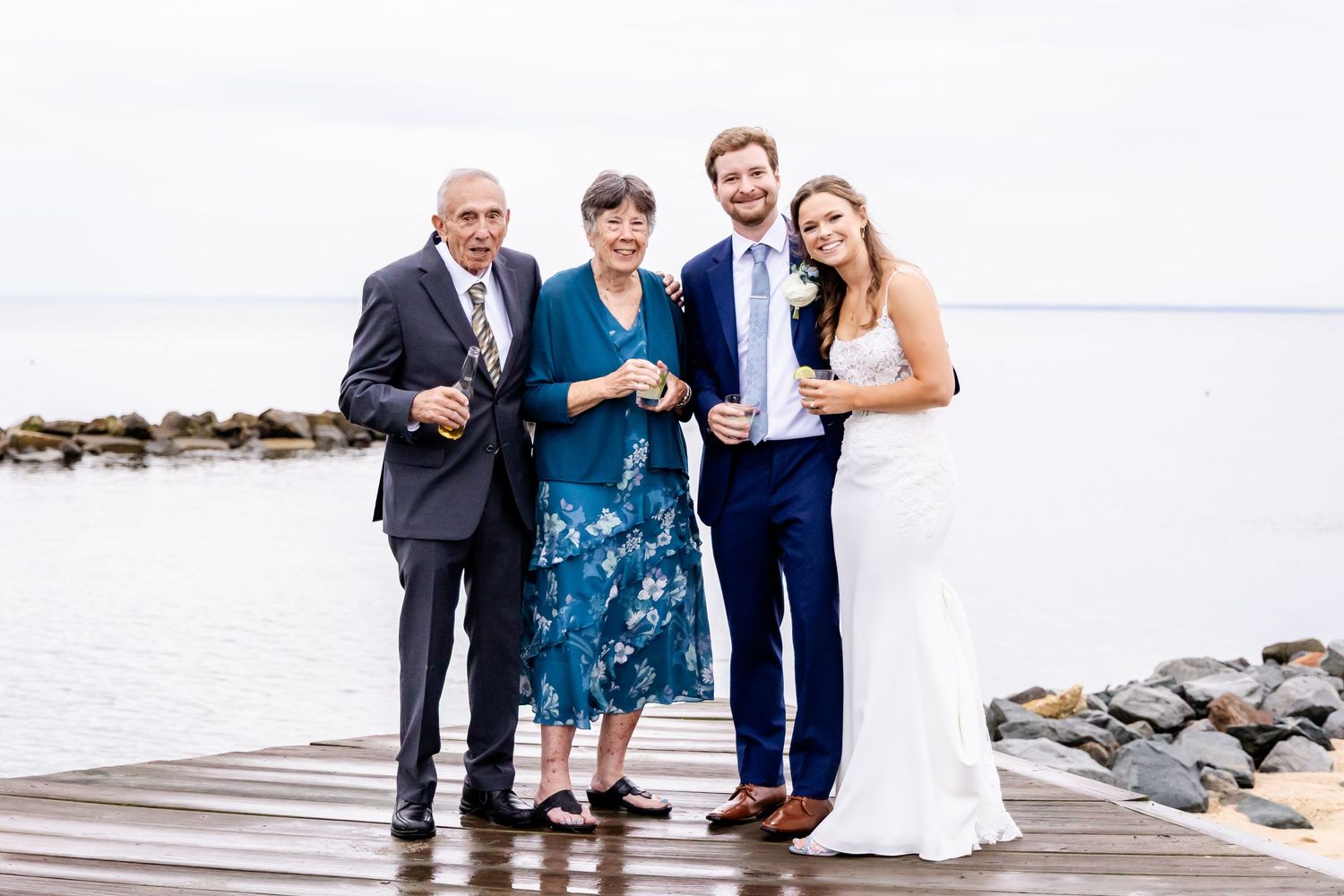 Wedding party poses together on a dock overlooking the water.