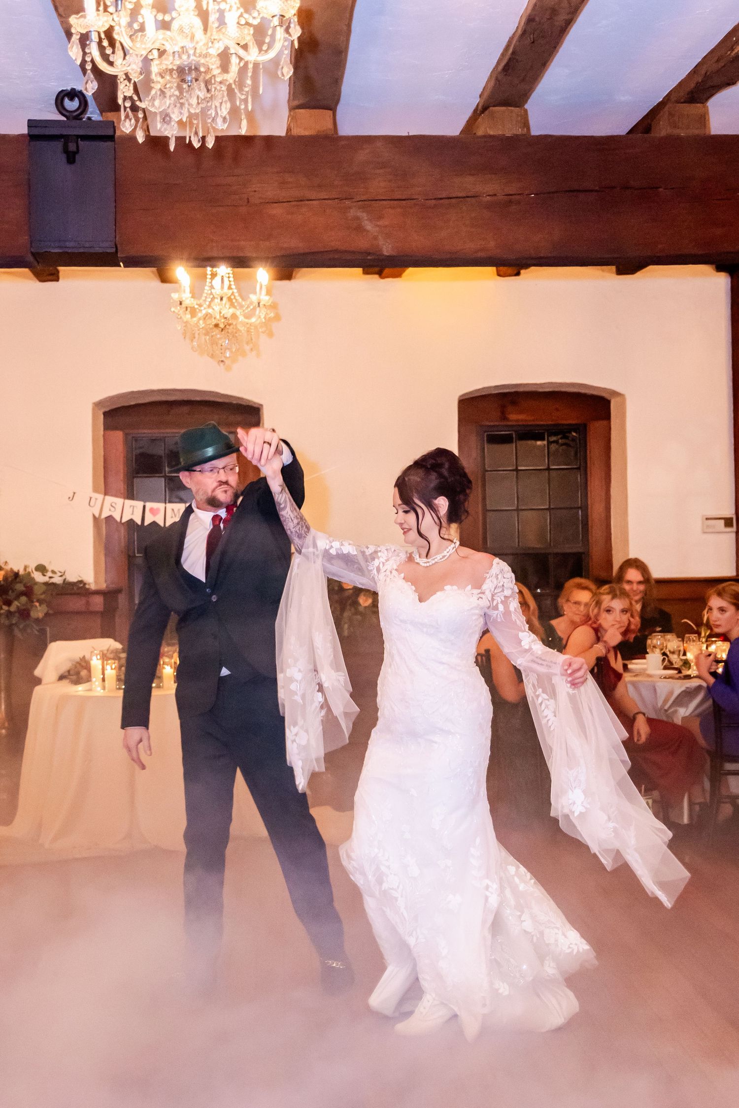 Couples dancing on a misty dance floor with dramatic lighting and wooden beam ceiling.